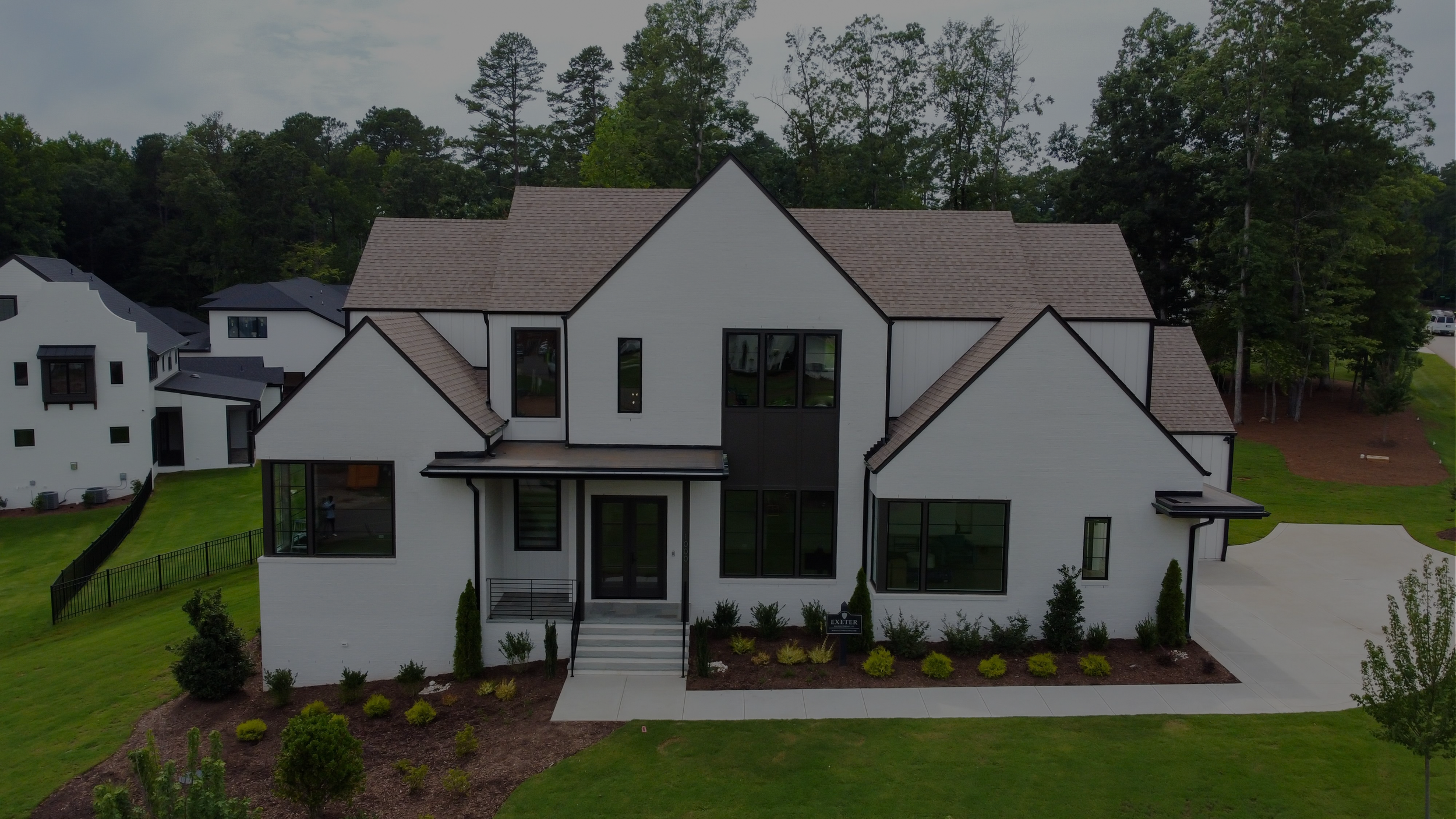 House exterior with white siding, exposed porch framing, and ladders during construction