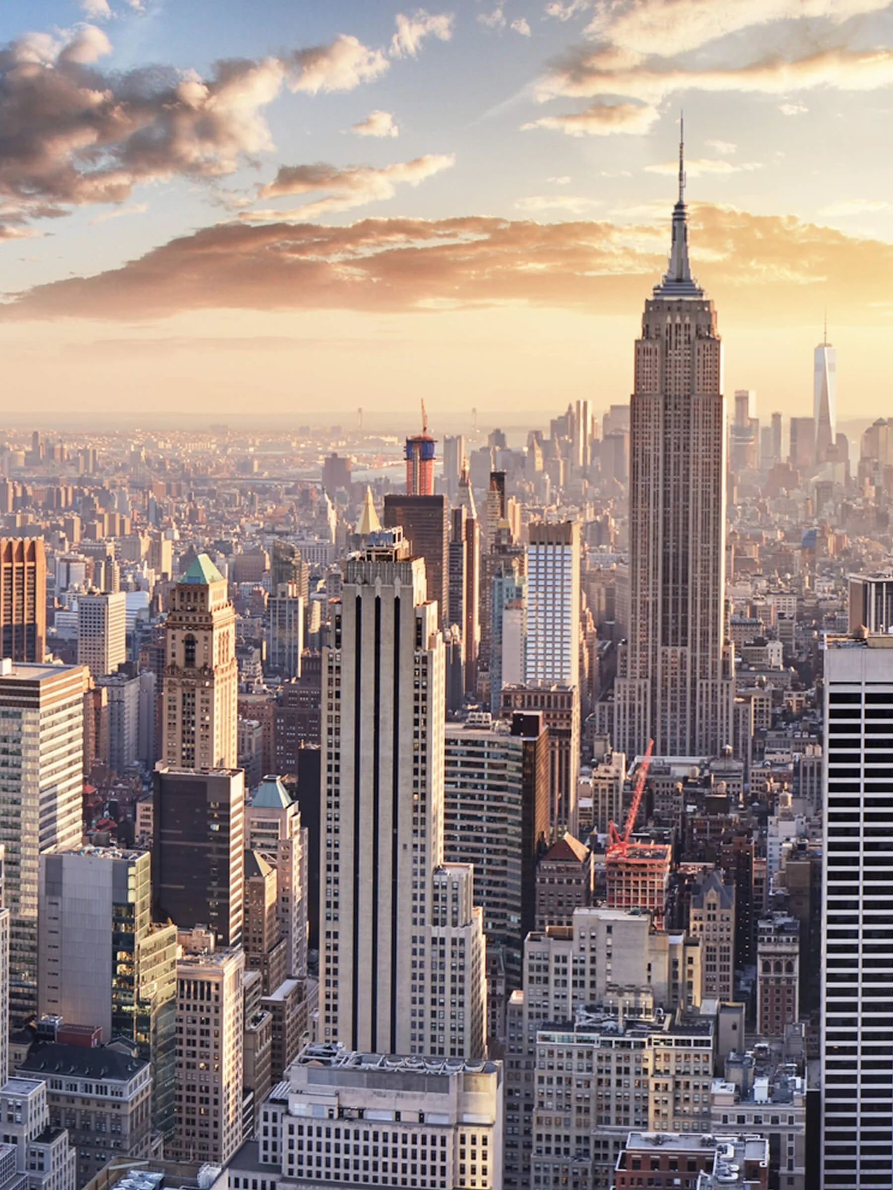 Skyline of New York City with the Empire State Building during sunset, showing tall skyscrapers and cityscape.