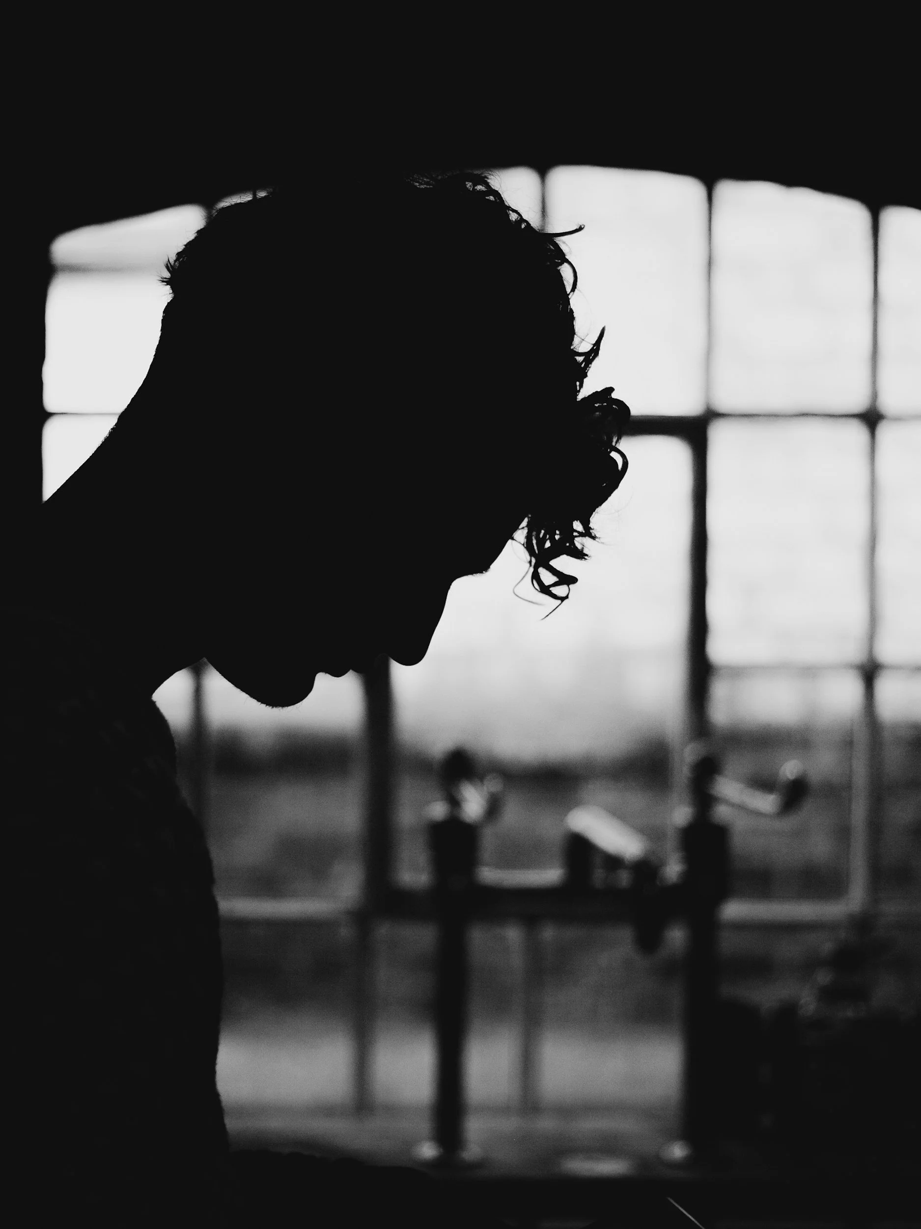 Black and White image of person with their head hanging in front of bars