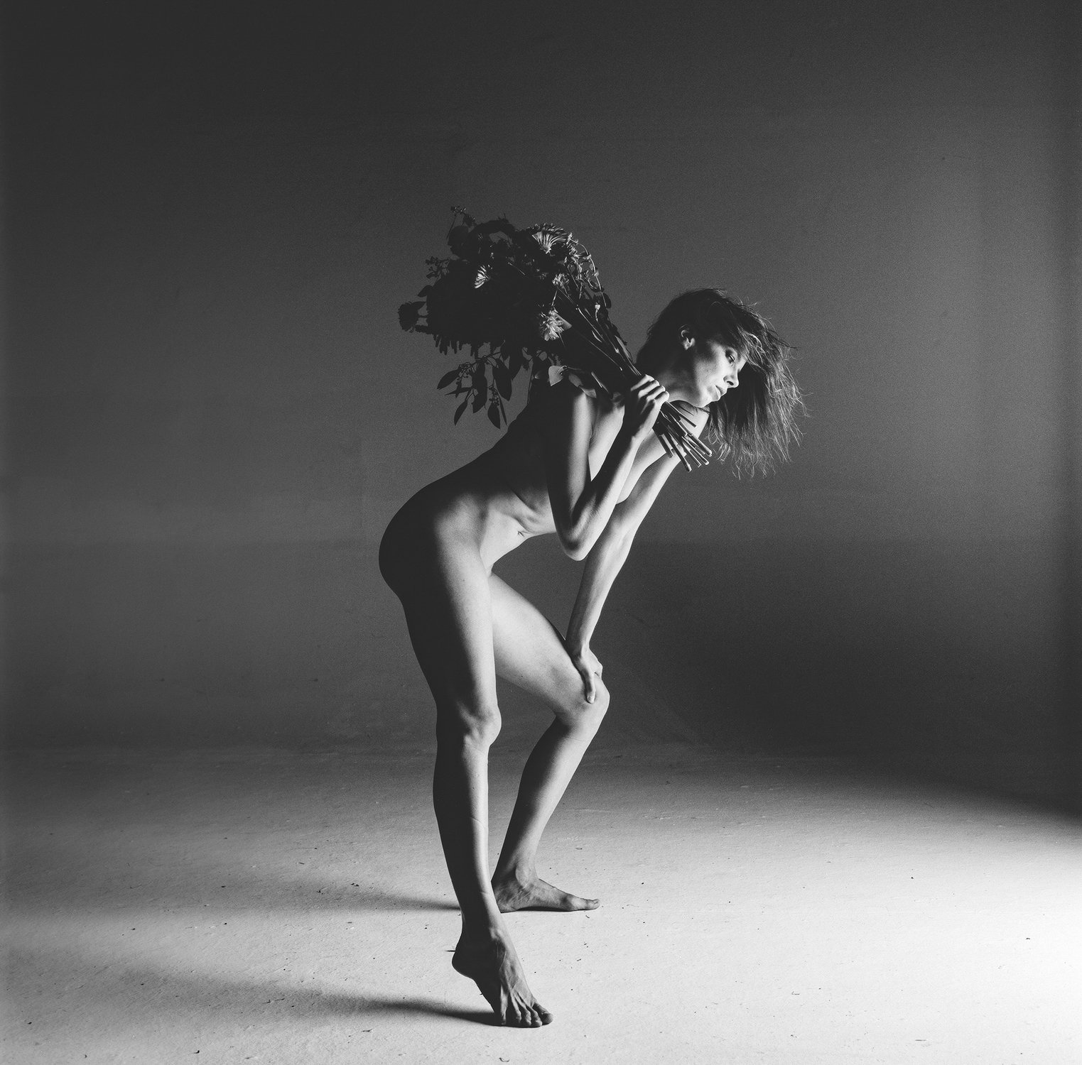 Black and white photo of a person with a bouquet of flowers.