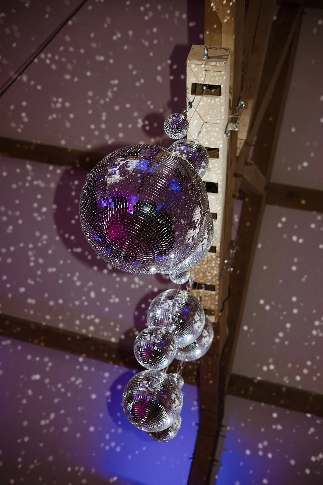 Multiple disco balls hanging from the ceiling, casting reflective patterns of light onto the ceiling and walls.