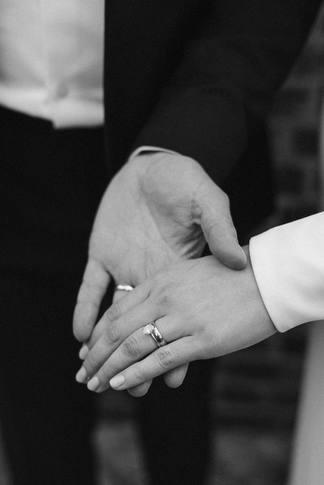 Close-up of a couple holding hands, with wedding rings, during a wedding ceremony.