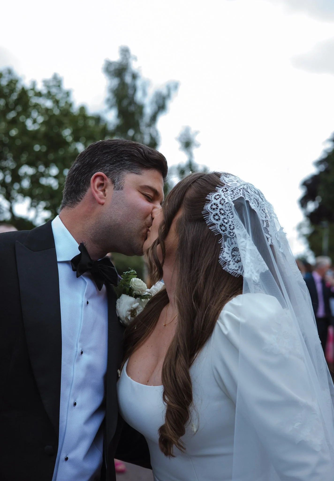 Bride and groom kissing during their wedding ceremony outdoors.