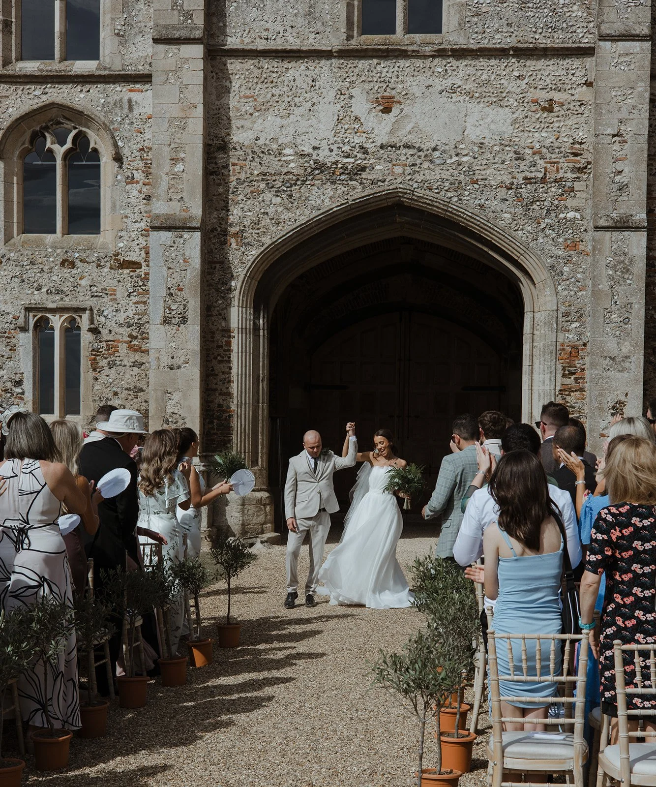 A bride and groom dancing outside a stone church with wedding guests watching.