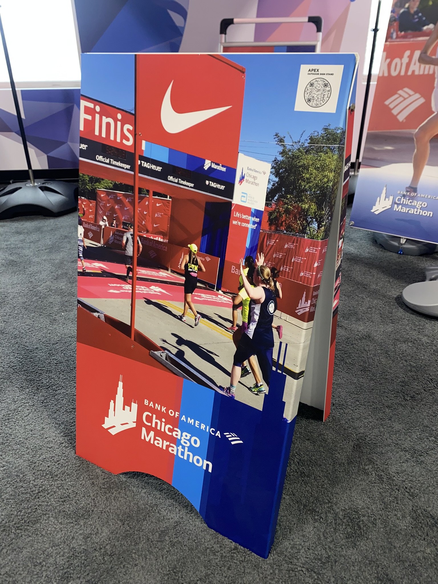 A promotional display for the Chicago Marathon, featuring runners crossing the finish line, with branding from Nike, Bank of America, and other sponsors, and a large finish line sign.