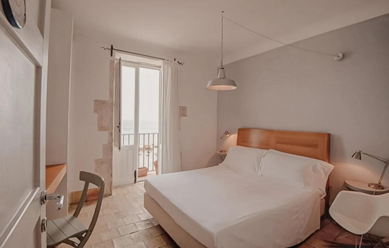 A bedroom with a bed, nightstands, and balcony door with curtains.