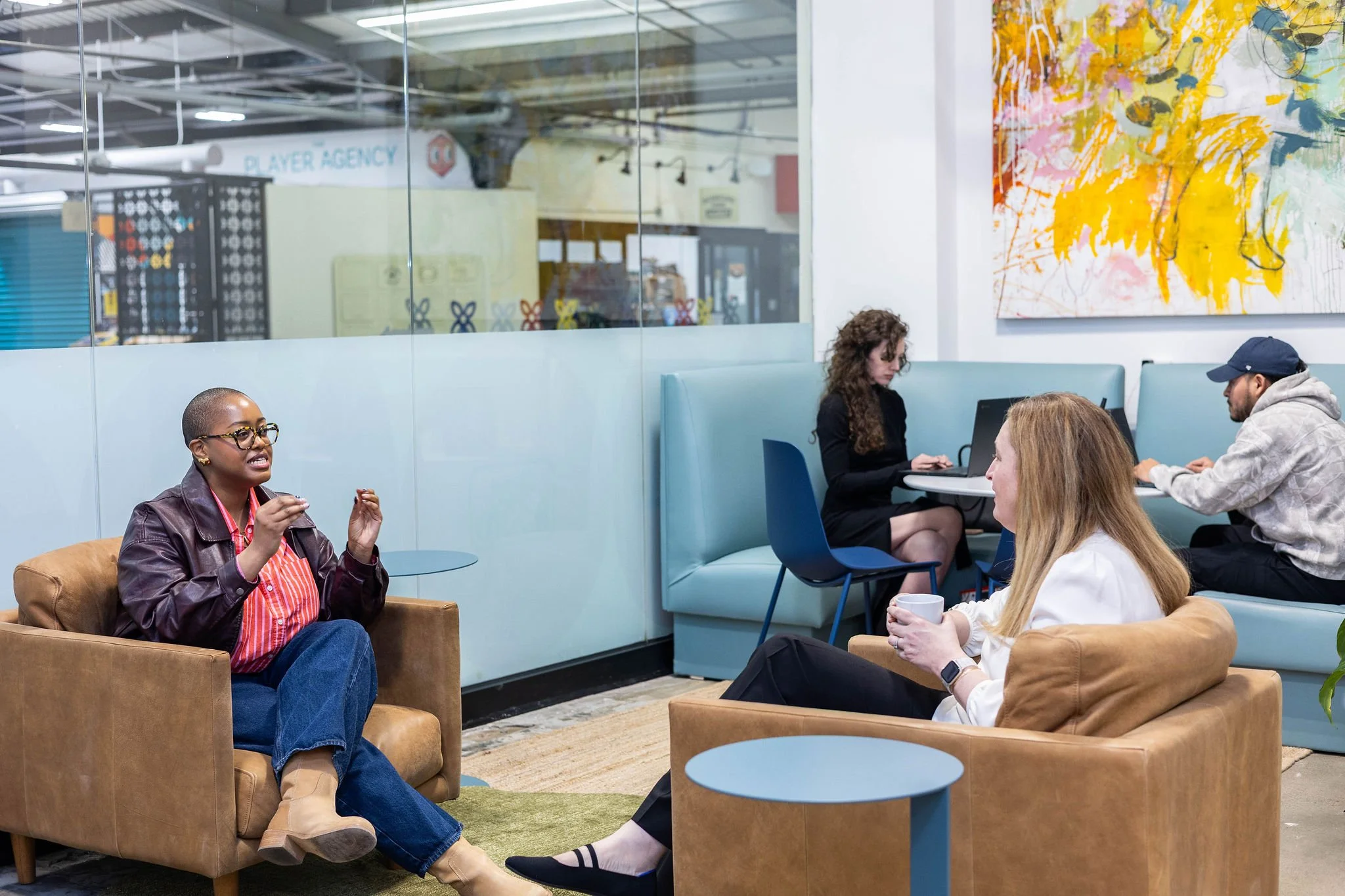 People working and engaging in conversation in a modern colorful office lounge.