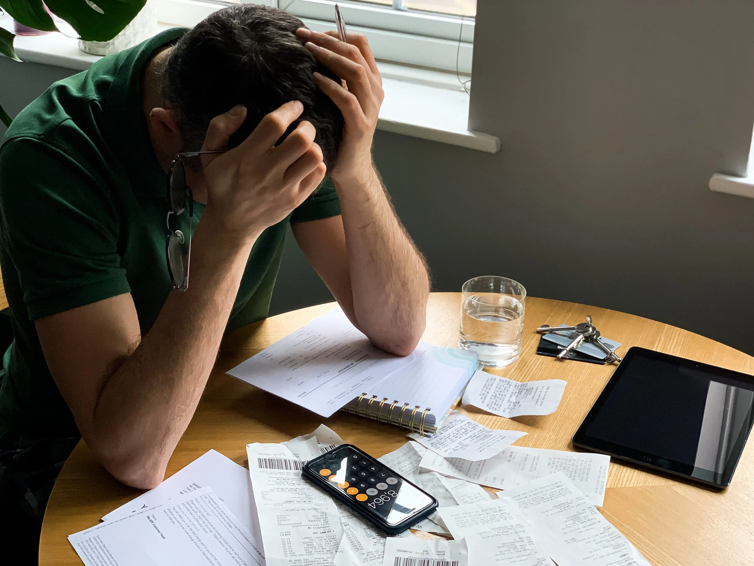 A man with his hands in his hair looking down frustrated at a pile of receipts.