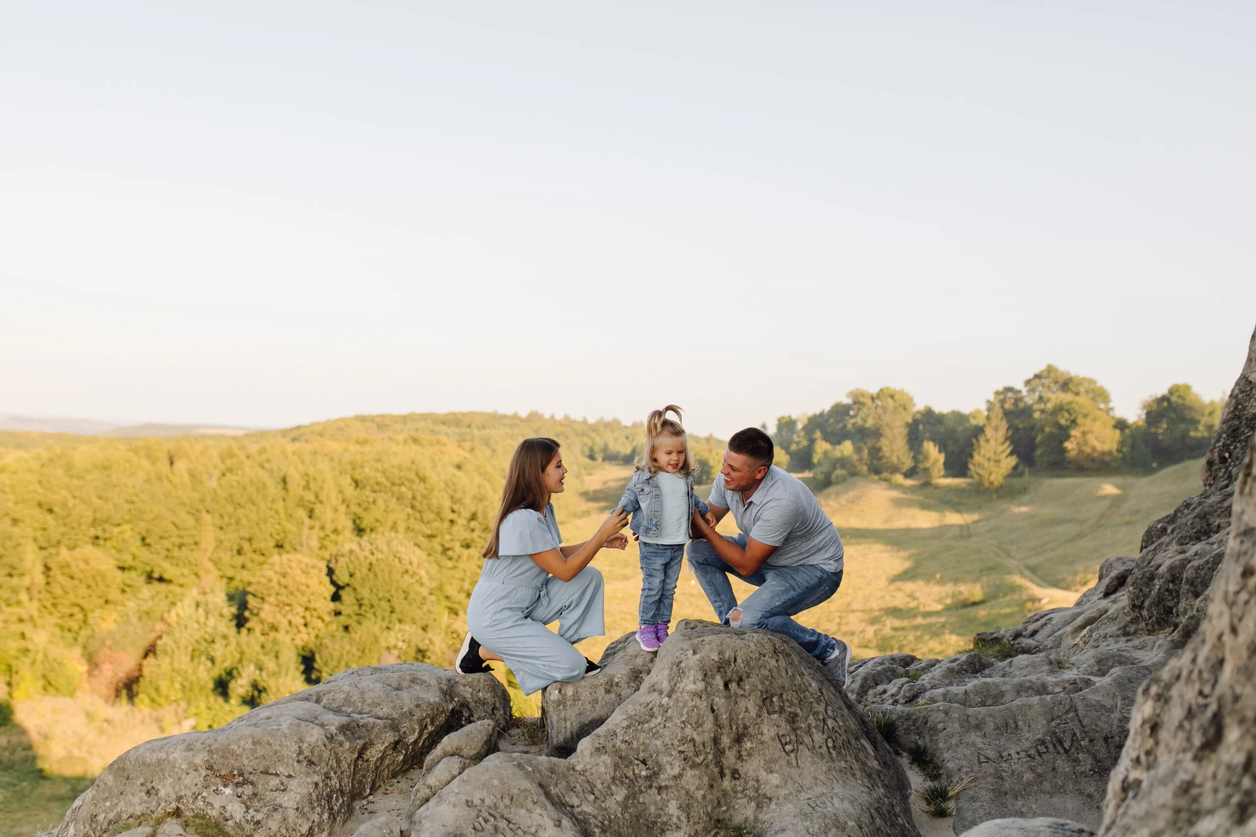 A young family taking a family photo on rocks.