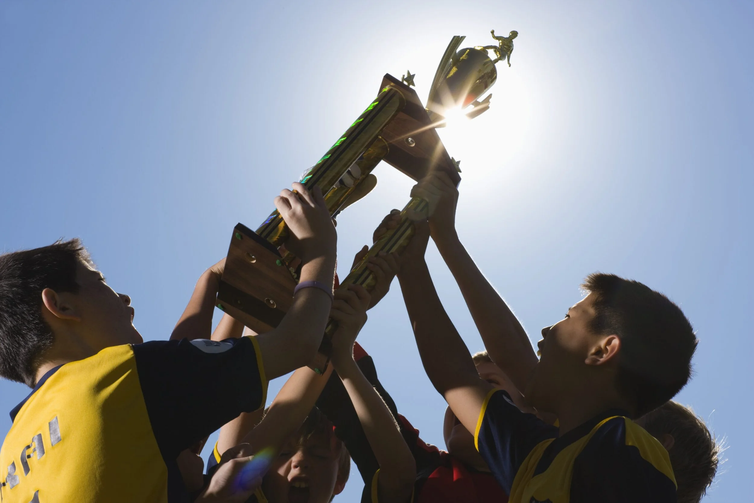 A team of athletes raising a trophy in air.