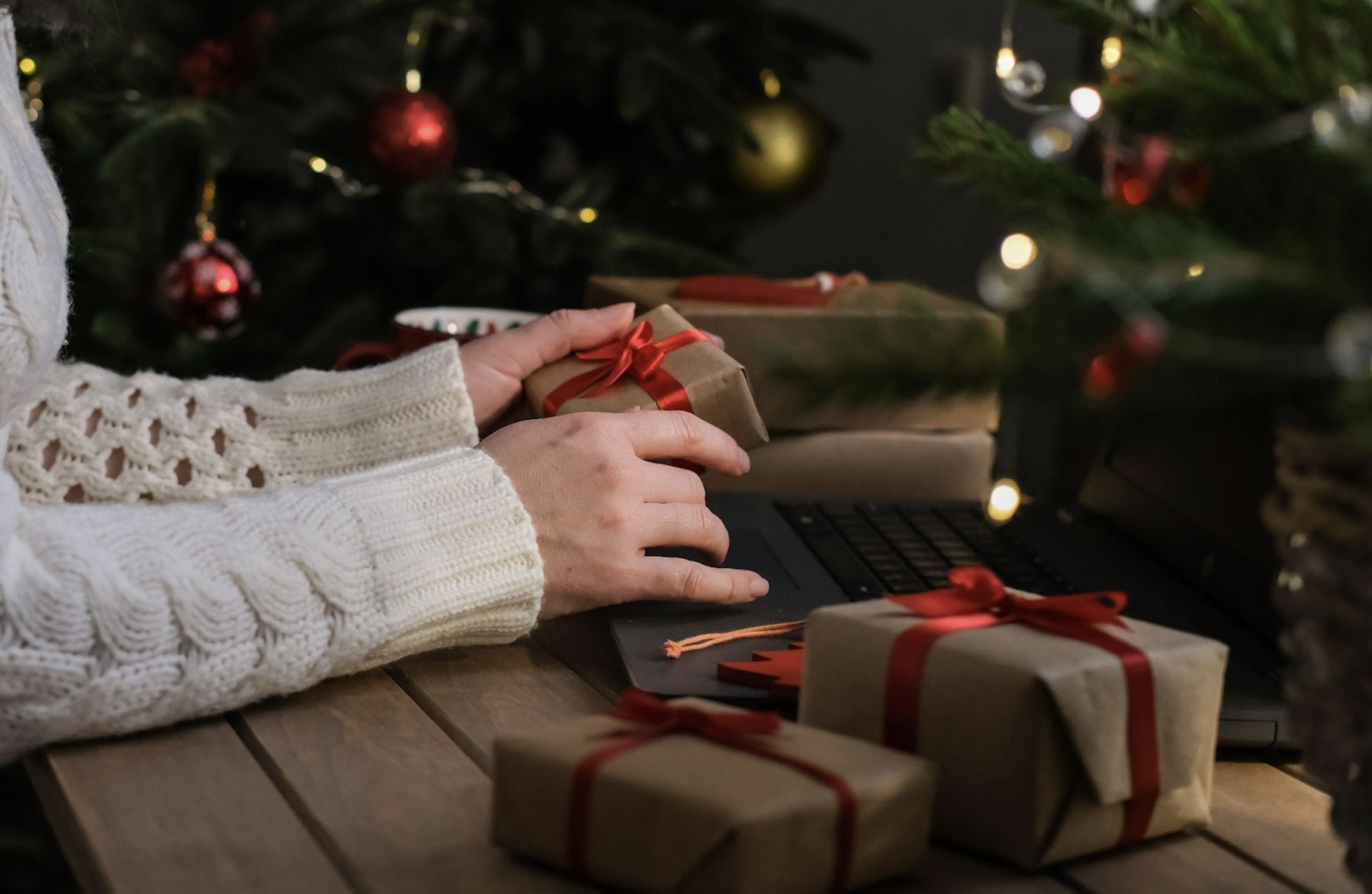 A person holding a small holiday gift box in their hands.