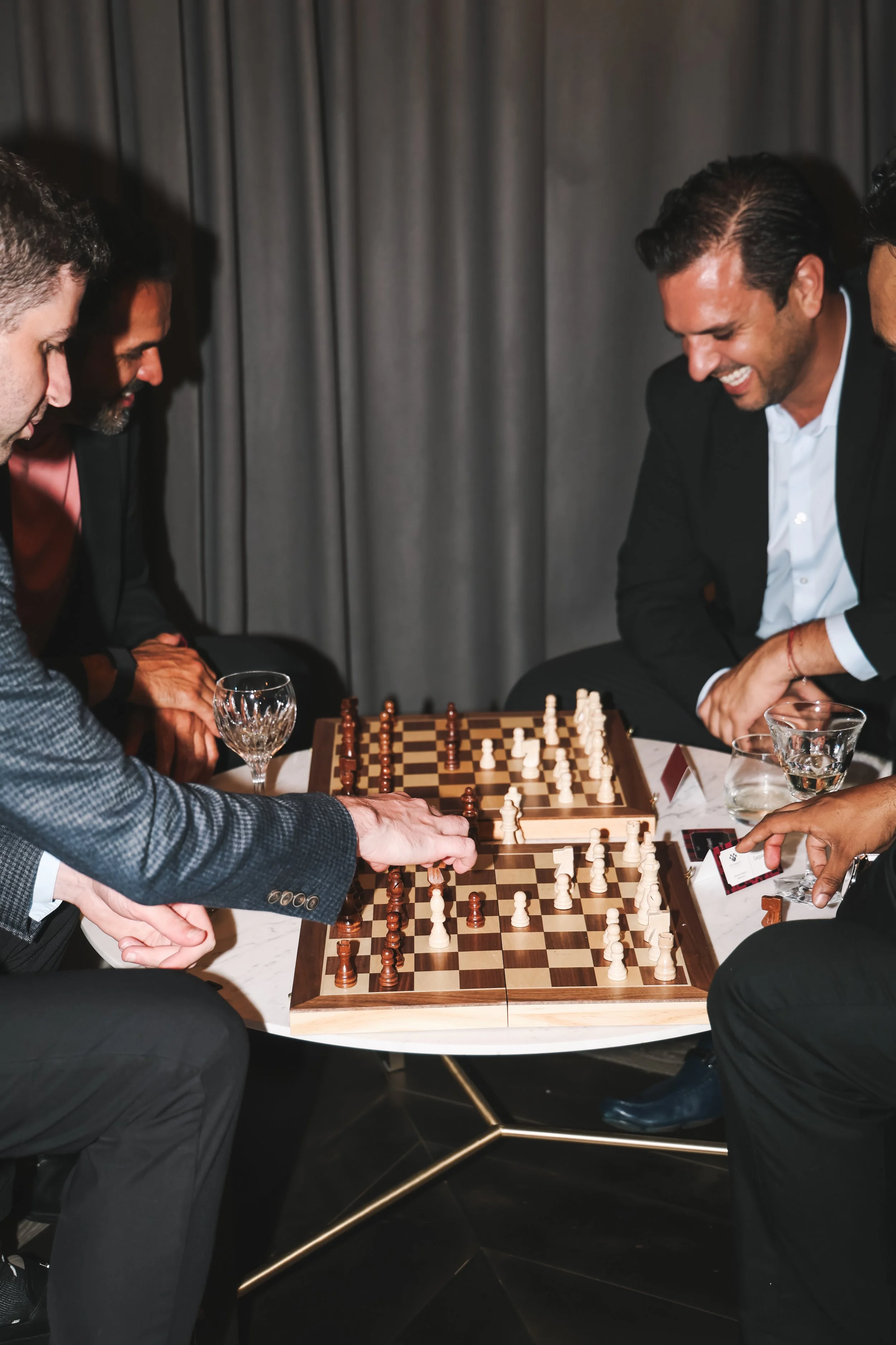 People playing chess at a table during a social event, with drinks present.