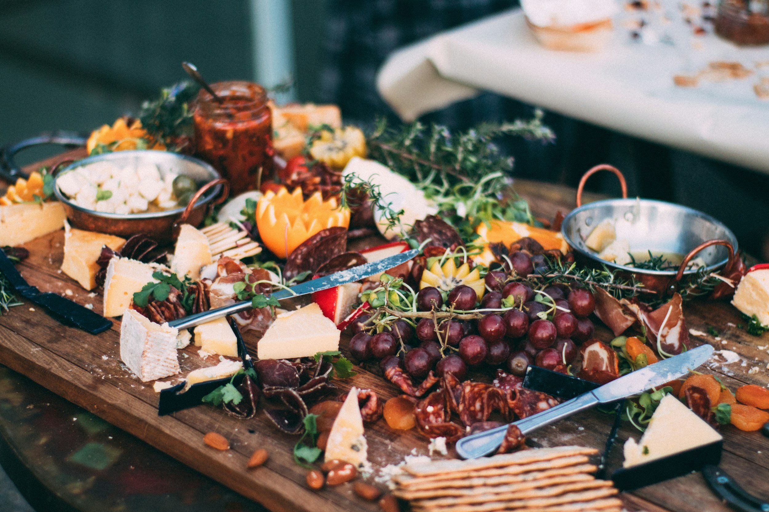 Image of a rustic charcuterie board display with crackers, cheeses, meats, fruits, and dips.