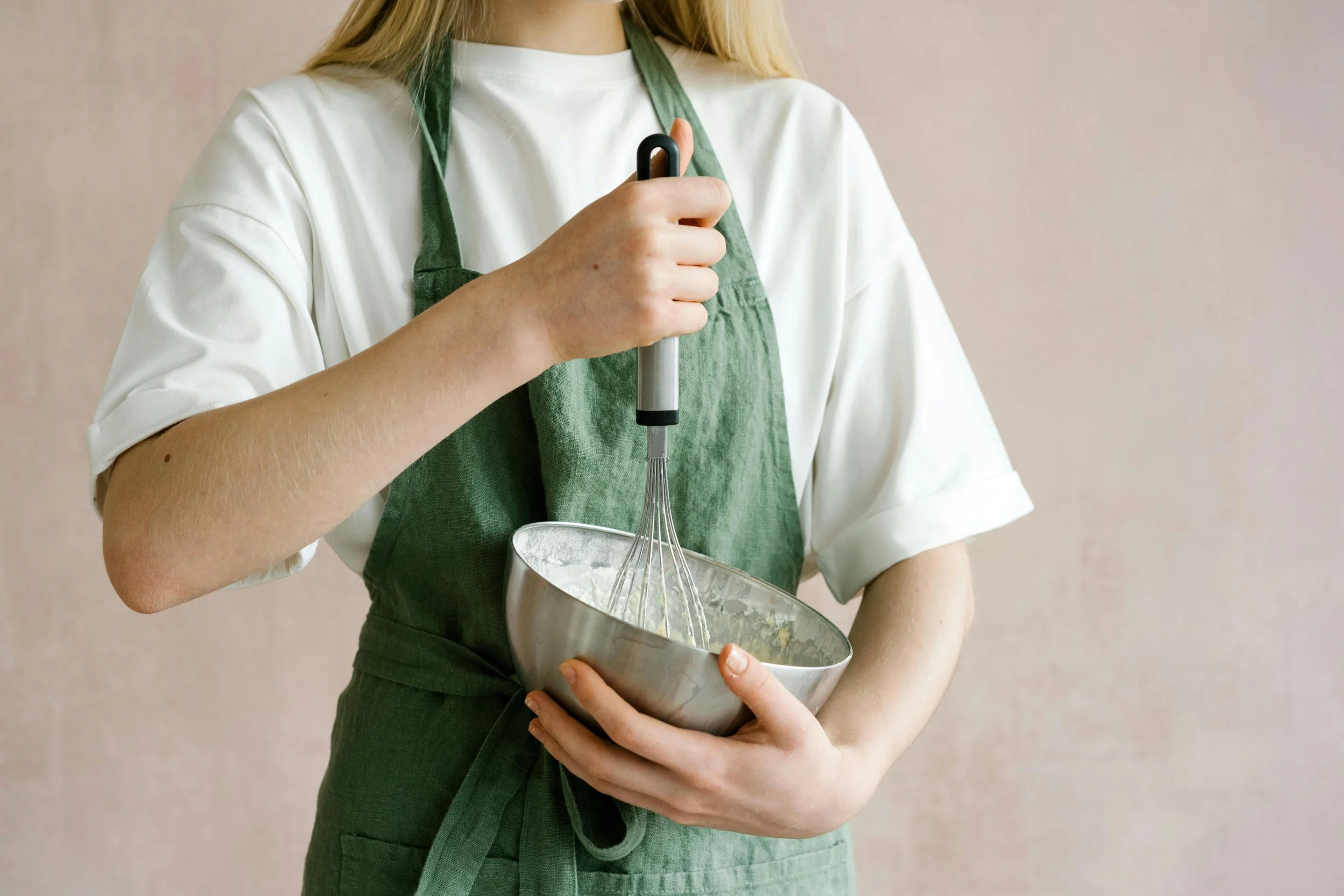 Image of blonde woman stirring a mixture in a silver bowl with a whisk.
