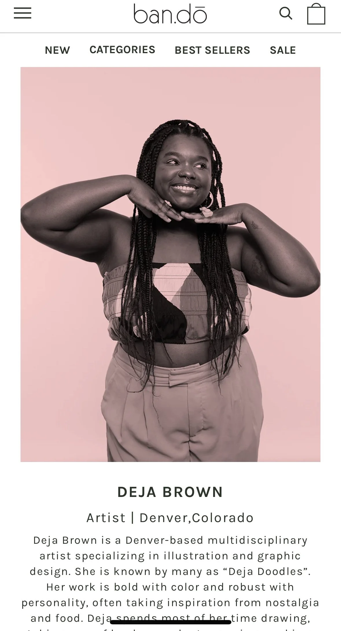 A woman with braided hair smiling and posing with her hands near her face, wearing a strapless top and beige pants, against a pink background.