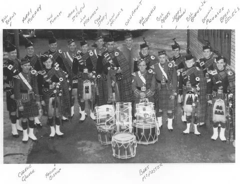 A group of 15 people in traditional Scottish attire, including kilts and sporrans, standing outdoors in a semi-circle formation, with several drums in the center. Handwritten notes surround the photo, mentioning names, musical roles, and descriptions