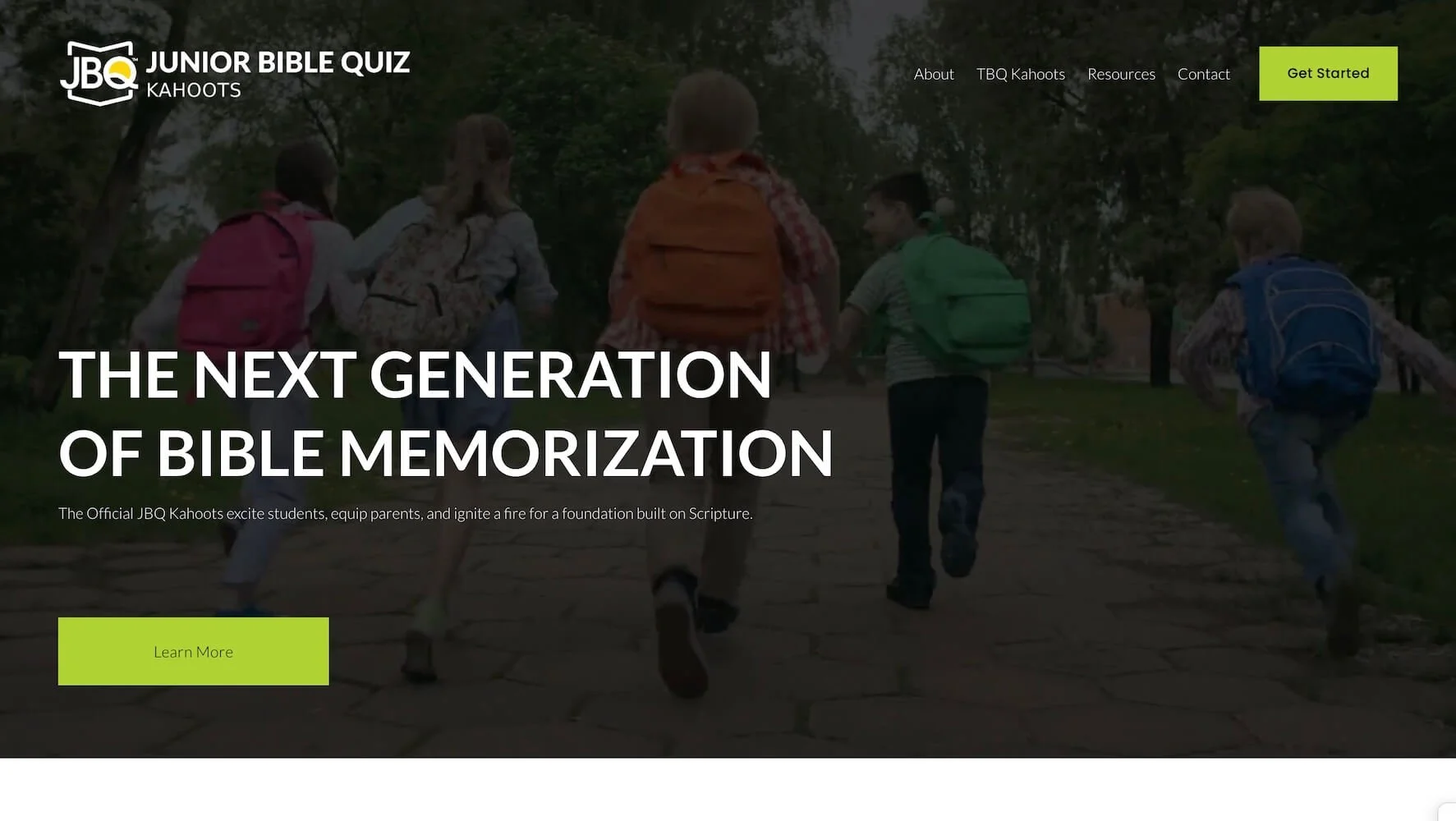 Children with backpacks walking and running outdoors on a pathway surrounded by trees.
