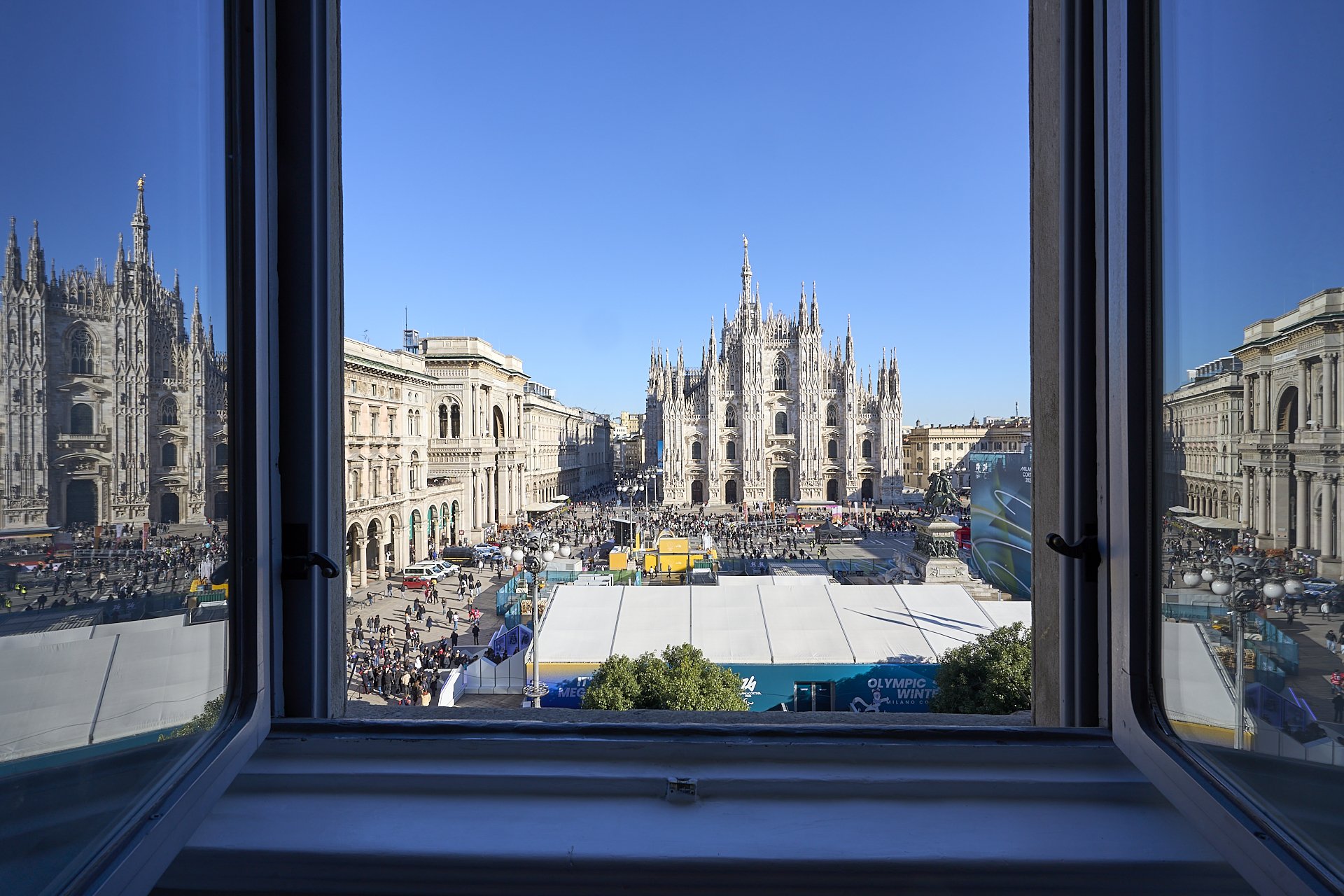 Vista di Piazza del Duomo a Milano, con il Duomo e le strade affollate viste da una finestra aperta.