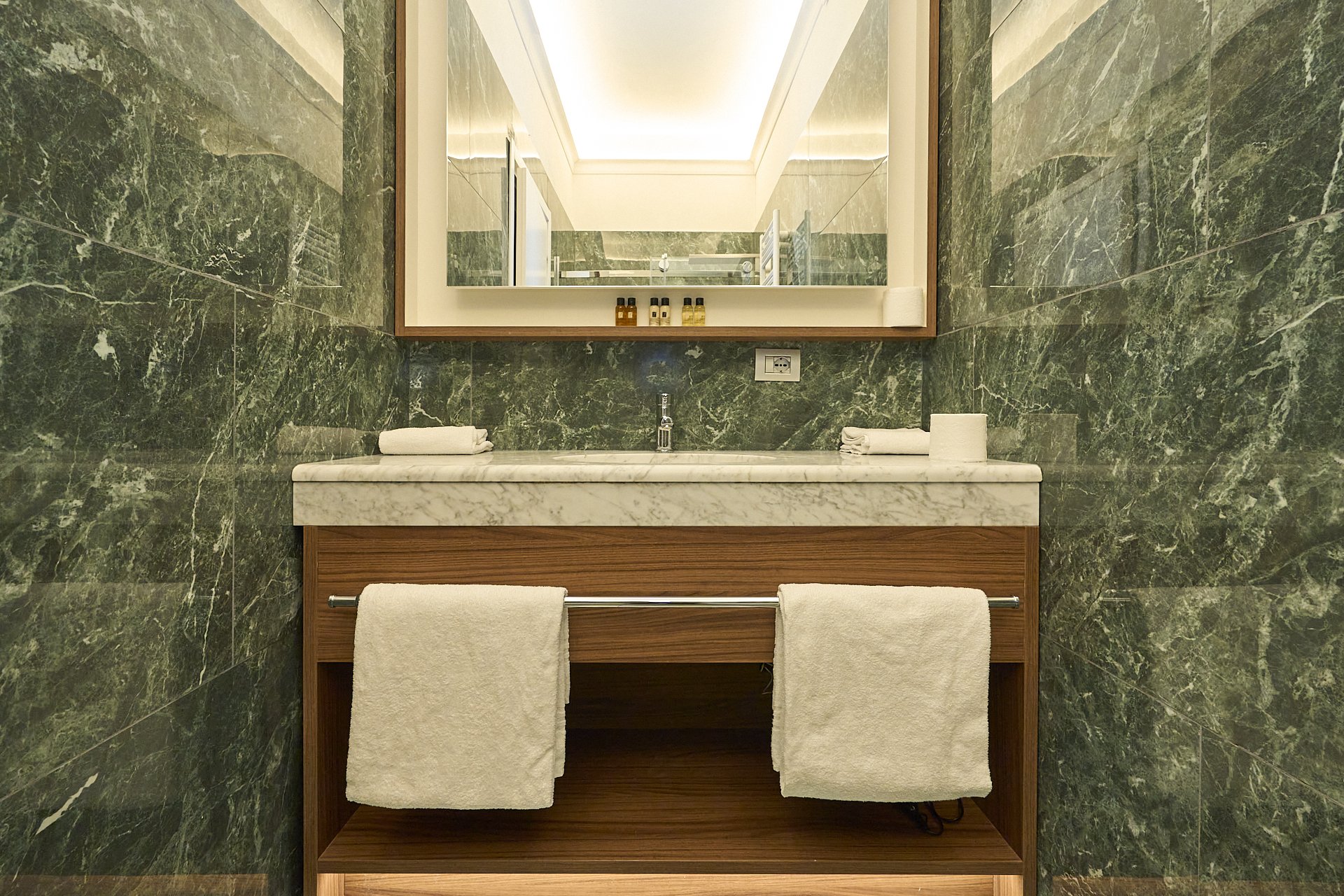  Specchio sopra un lavabo in marmo con asciugamani bianchi e prodotti per il bagno.