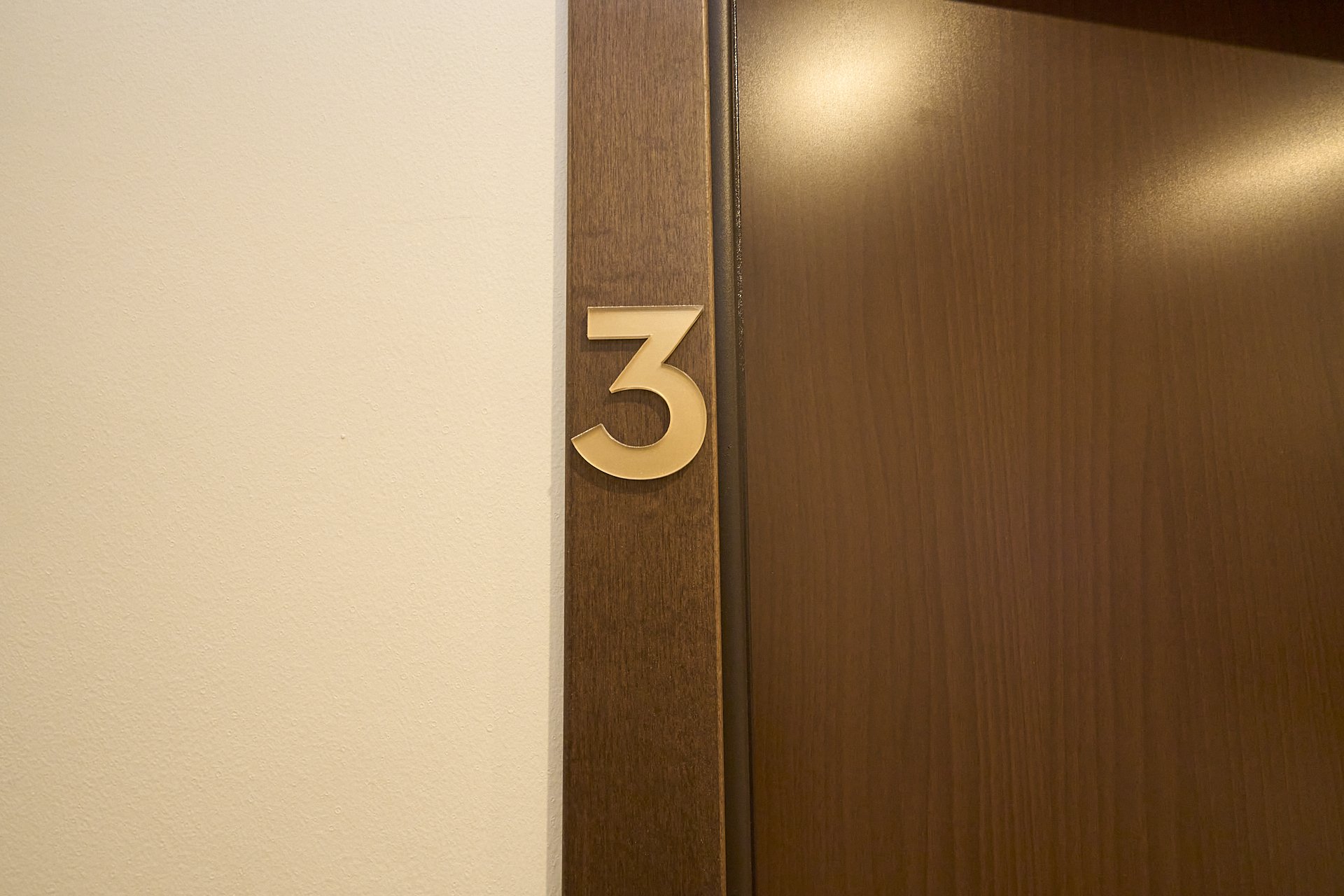 Numero 3 apposto sulla cornice di una porta di legno.