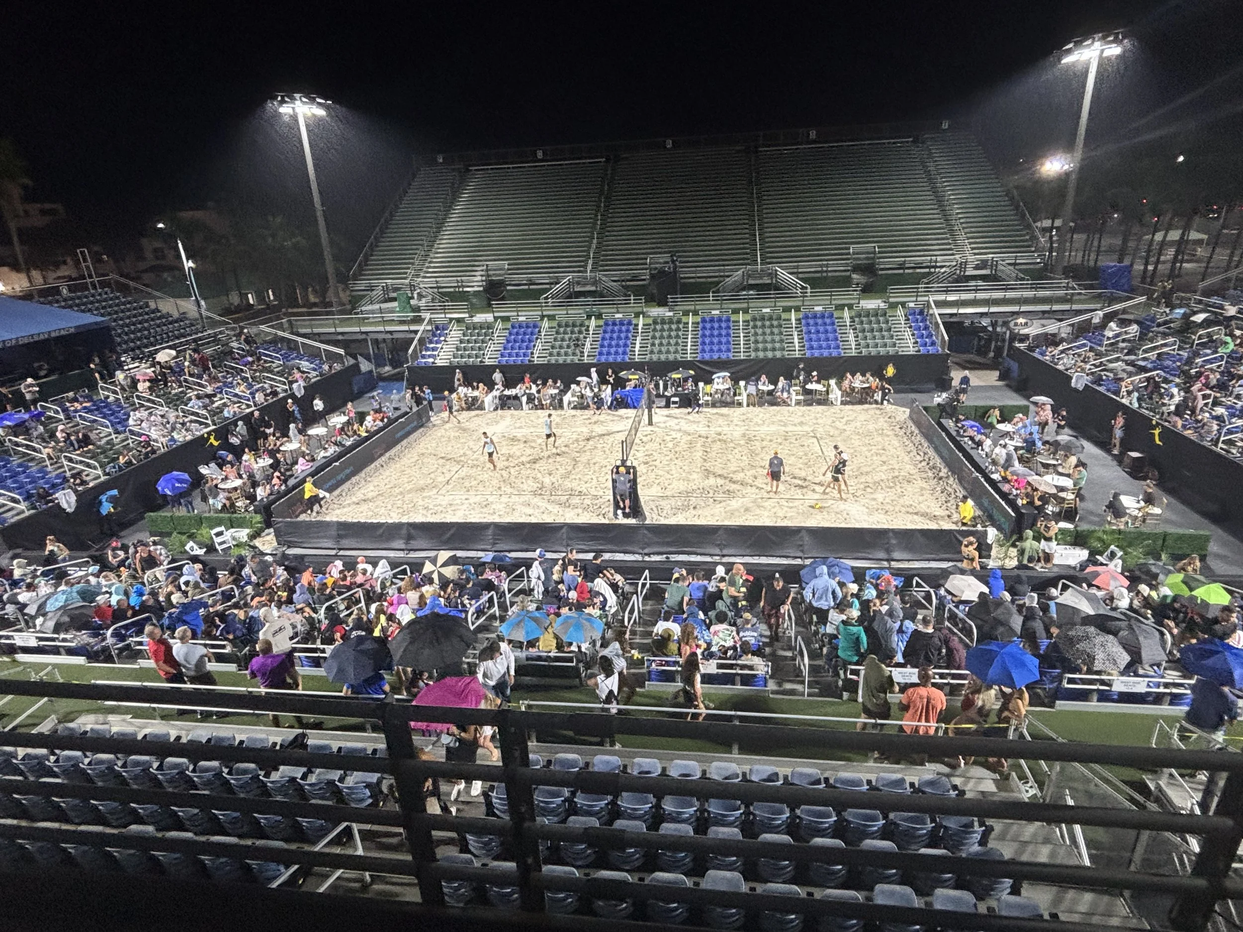 View from stadium seating of an evening AVP volleyball match