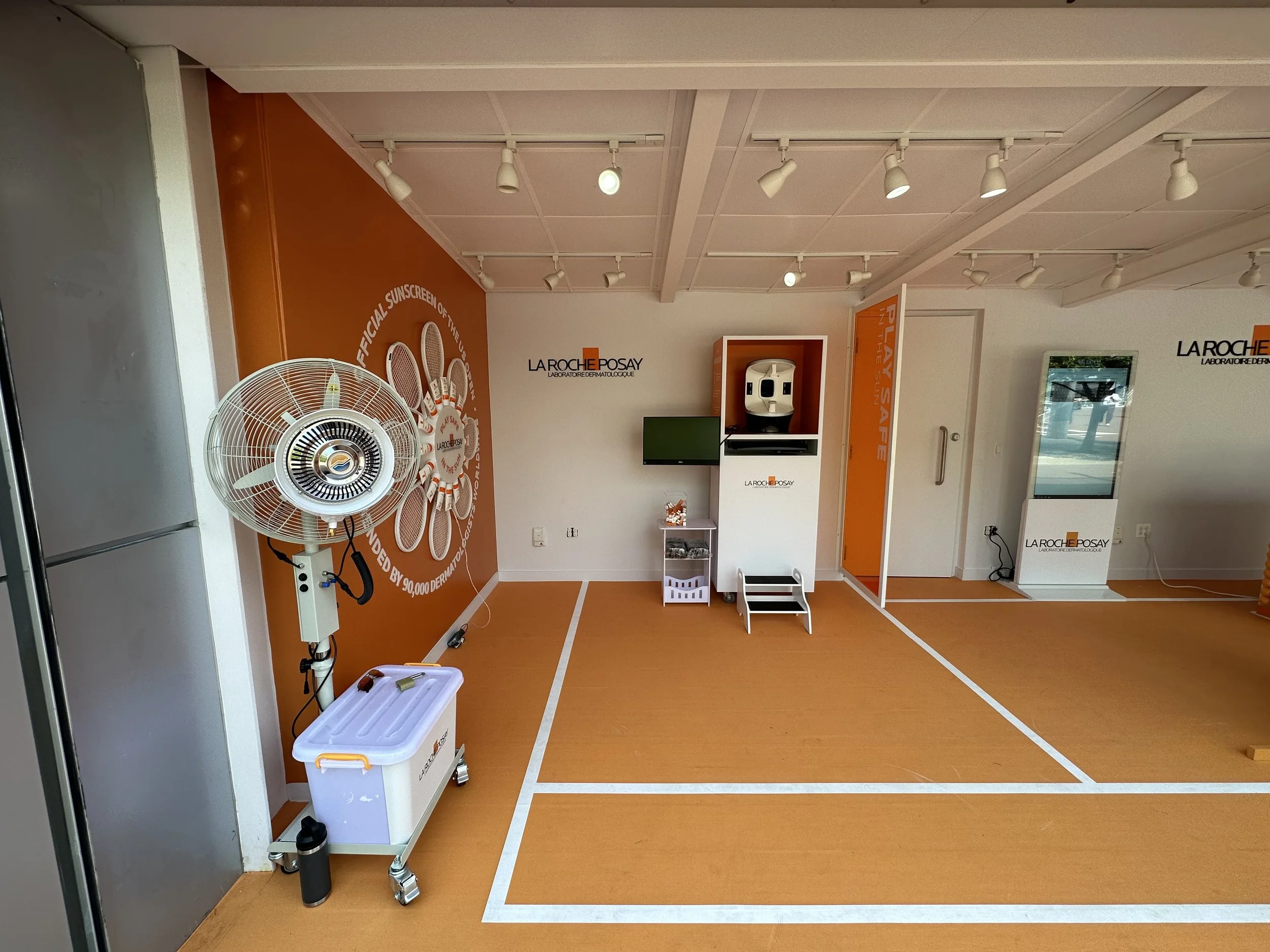 La Roche-Posay activation interior with sunscreen displays, cooling fans, and tennis court floor graphics.