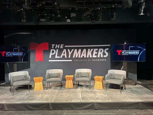 Panel stage with lounge chairs and The Playmakers backdrop