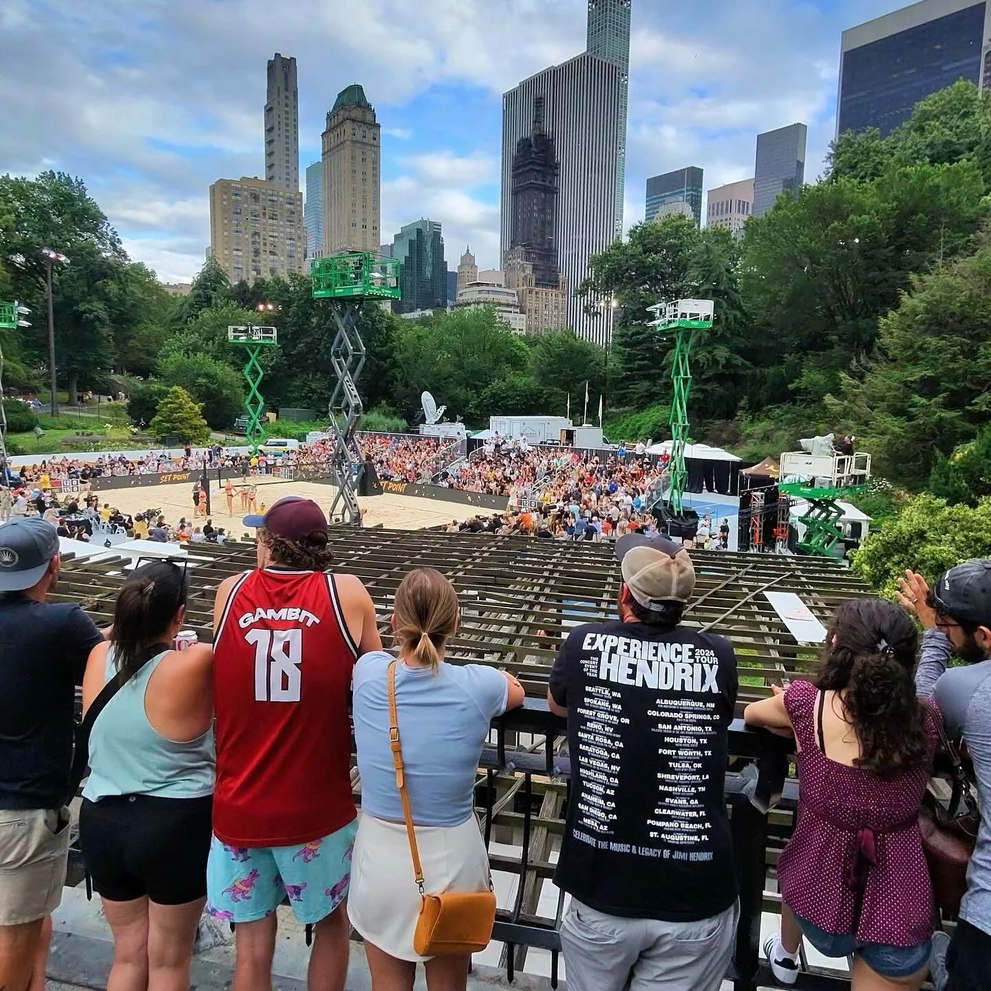 Guests overlooking an AVP court with the city skyline beyond
