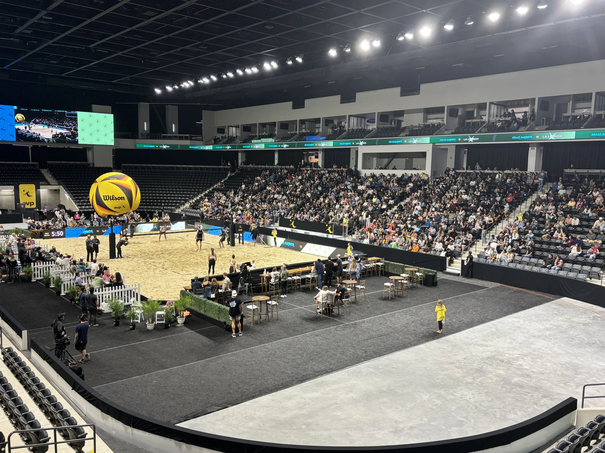 Nighttime AVP venue with courtside seating