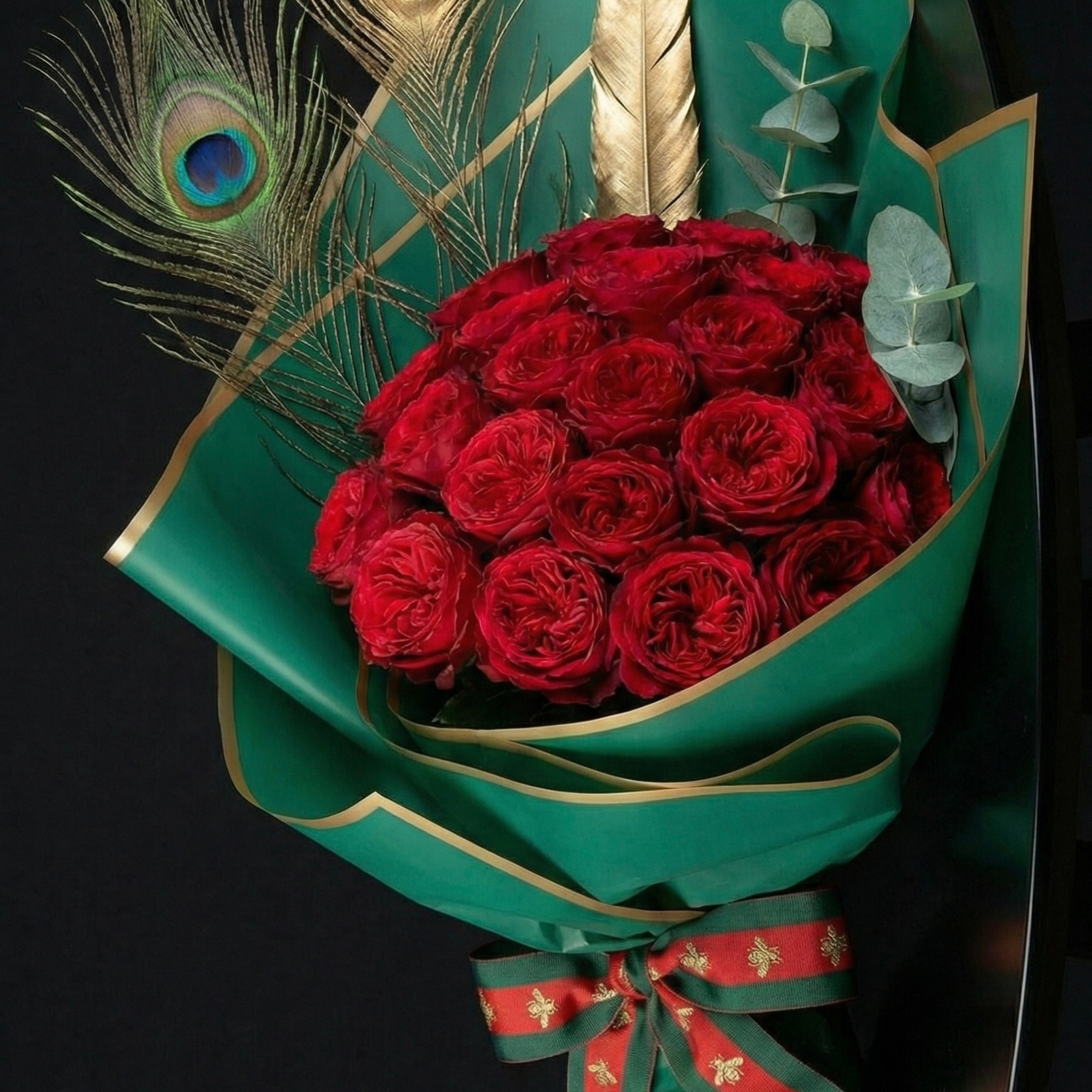 Make a statement this Valentine's Day. This luxury bouquet features deep red roses, peacock feathers, and a gold accent. Local flower delivery is available in Feeding Hills and Agawam.