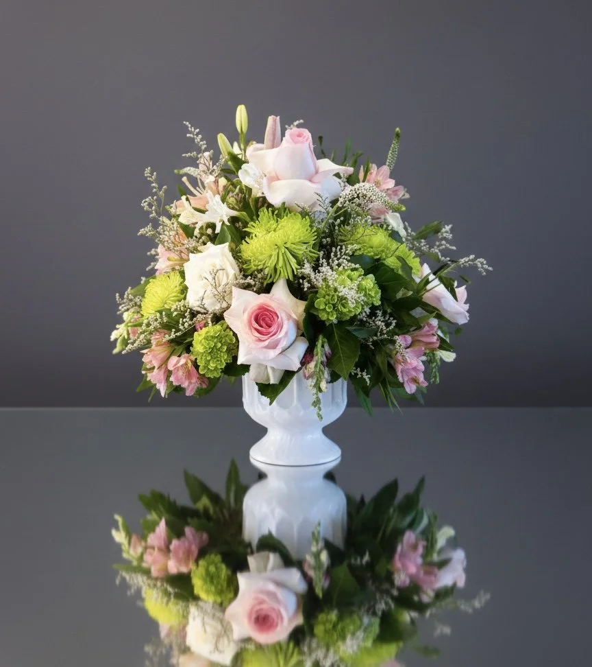 Pink and white rose funeral arrangement with green spider mums, lilies, alstroemeria and trachelium in white pedestal vase