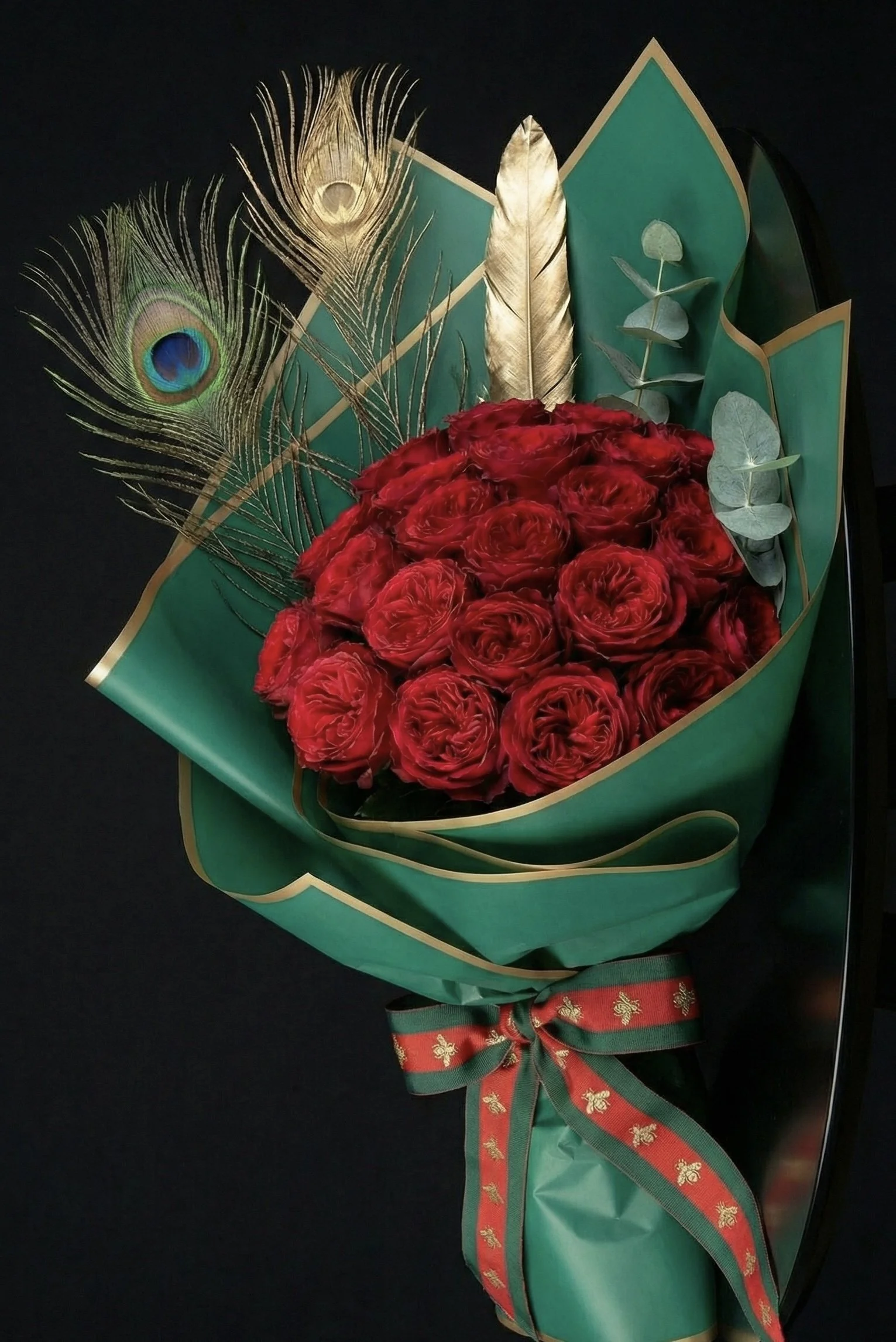 Make a statement this Valentine's Day. This luxury bouquet features deep red roses, peacock feathers, and a gold accent. Local flower delivery is available in Feeding Hills and Agawam.