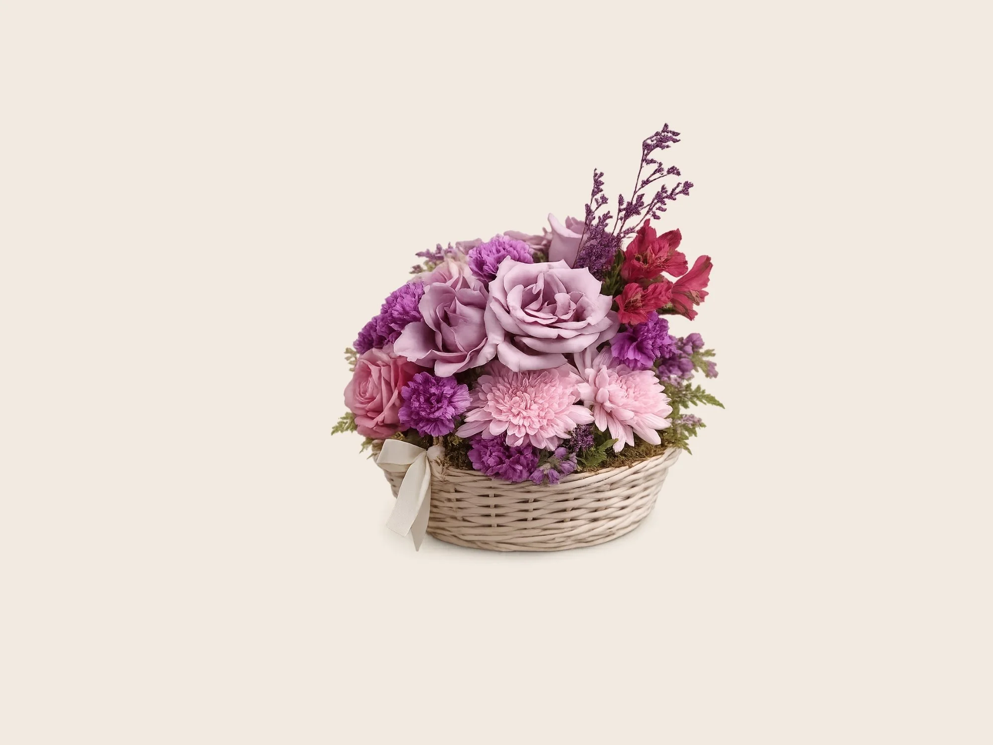A floral arrangement in a wicker basket with pink and purple flowers, decorated with a white ribbon, against a cream background.