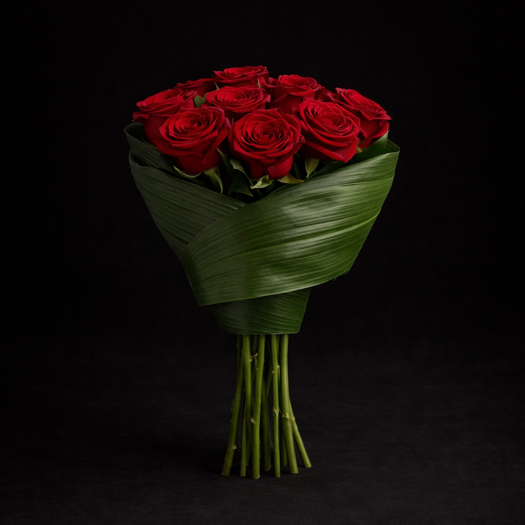 A couture  bouquet of premium red roses, wrapped in sculpted tropical foliage