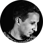 Close-up of a young man with short hair, looking downward, in black and white.