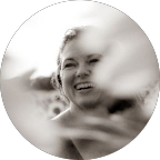 A smiling young girl outdoors, with a blurred background.