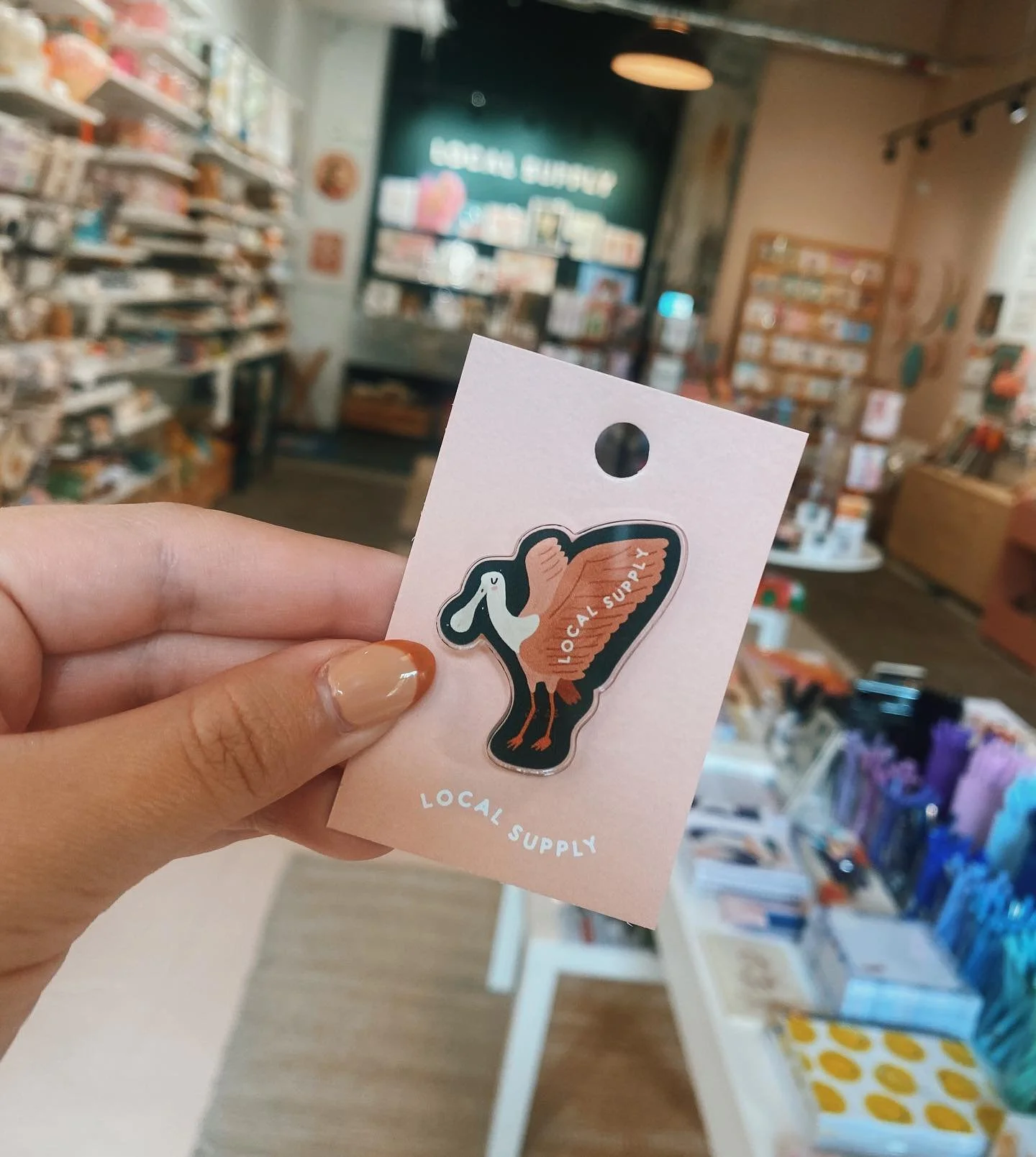 Y&rsquo;all! I got to illustrate this precious little Spoonbill Rosie for @localsupplybr and I am so obsessed with seeing it on a pin! 🤍😆 

also, my nails match perfectly with the color scheme which made my design heart soooooo full 💅🏻

#localbus