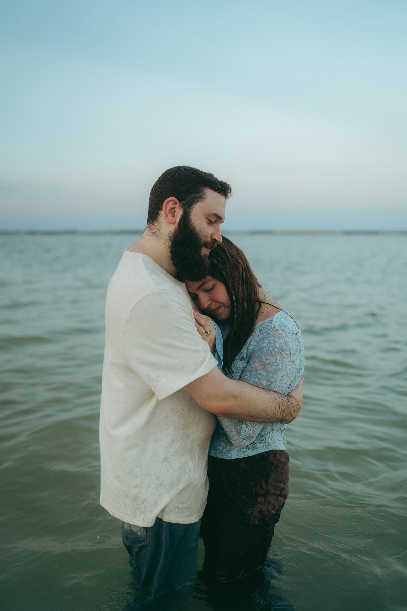 Una pareja abrazada en la orilla del mar, mostrando un momento de ternura y amor.