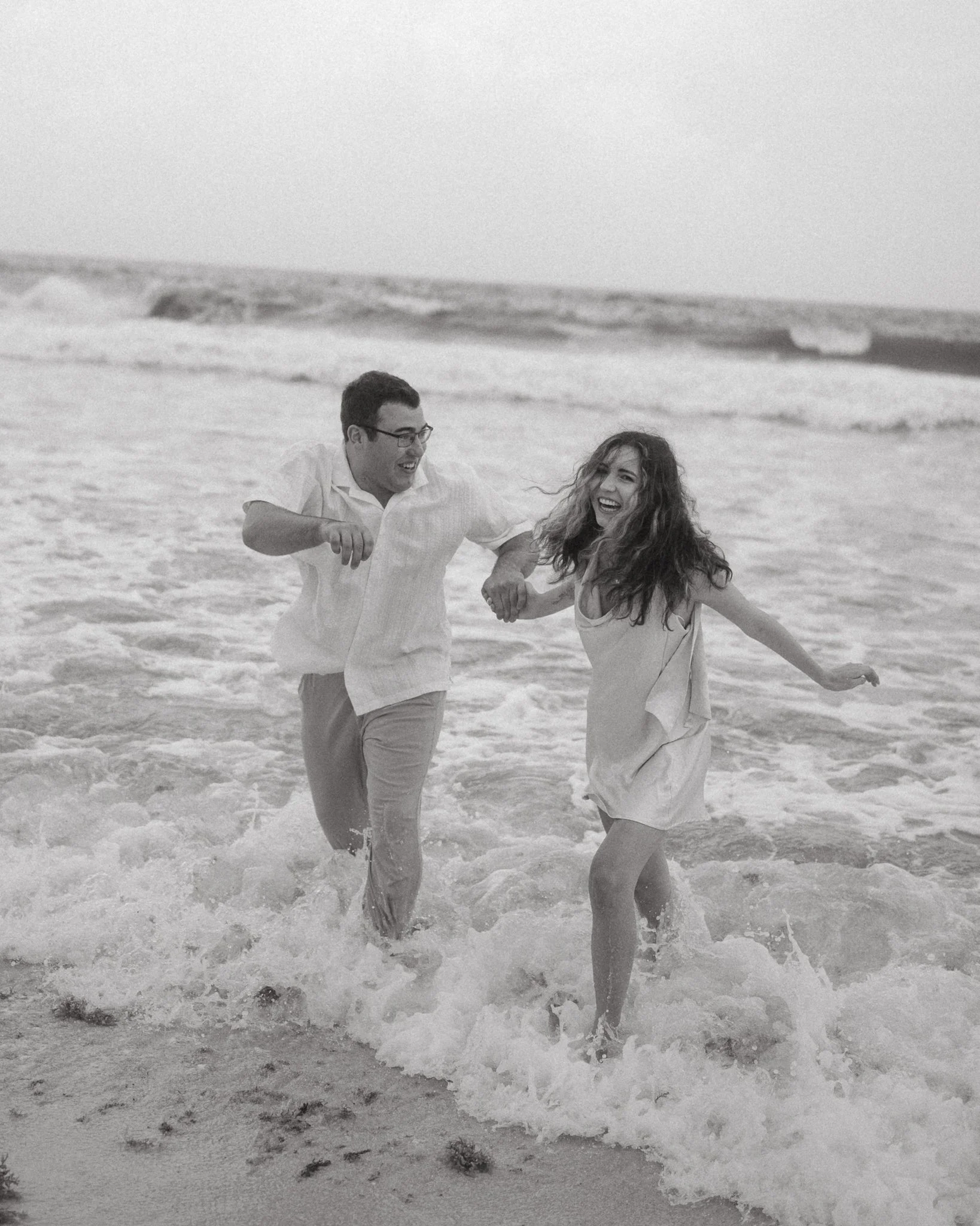 Una pareja feliz jugando en la orilla del mar, en la playa.