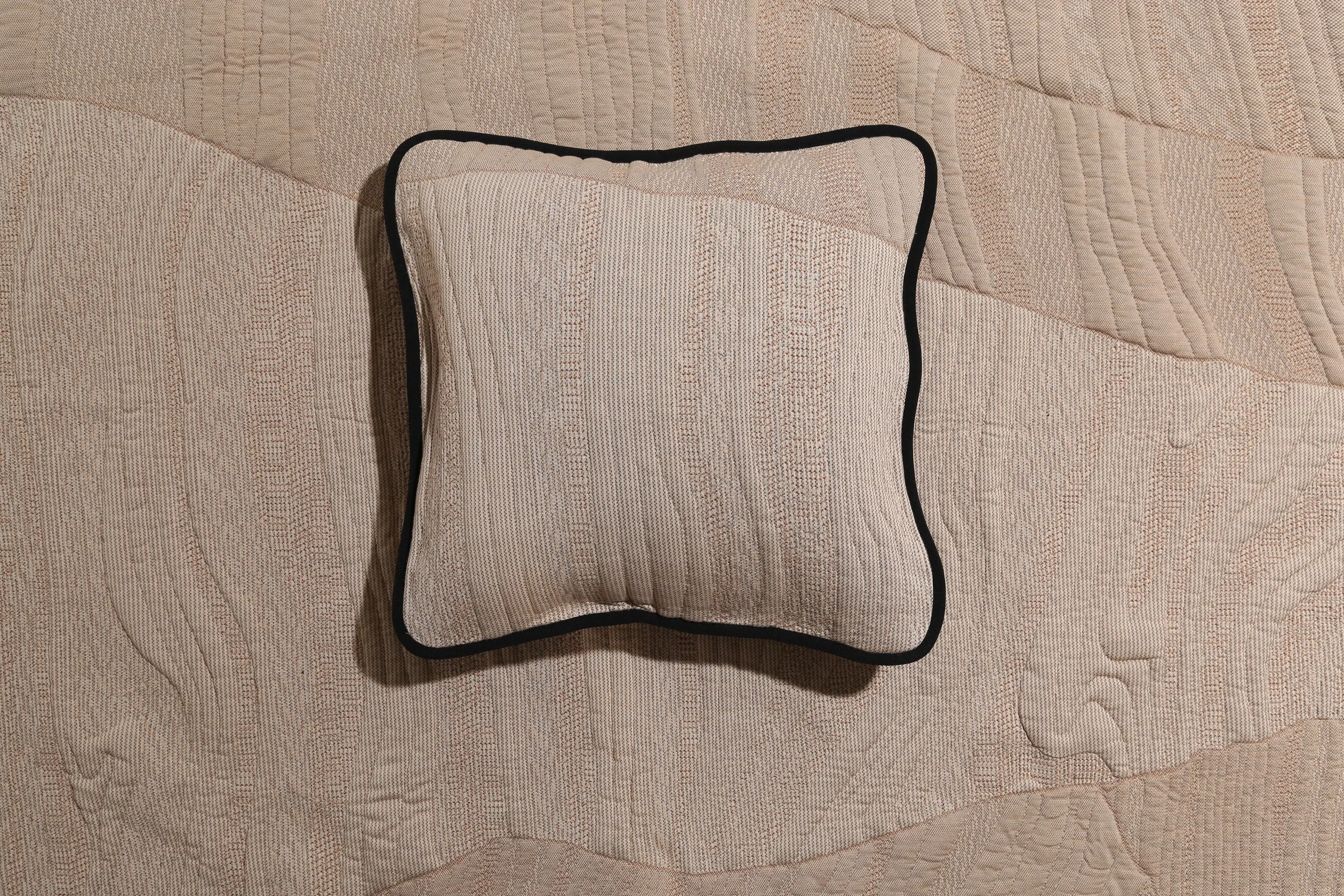 Square knit cushion in natural ecru with subtle texture and black piping, placed on a matching knit blanket. Textile development by Byborre for Browns London.