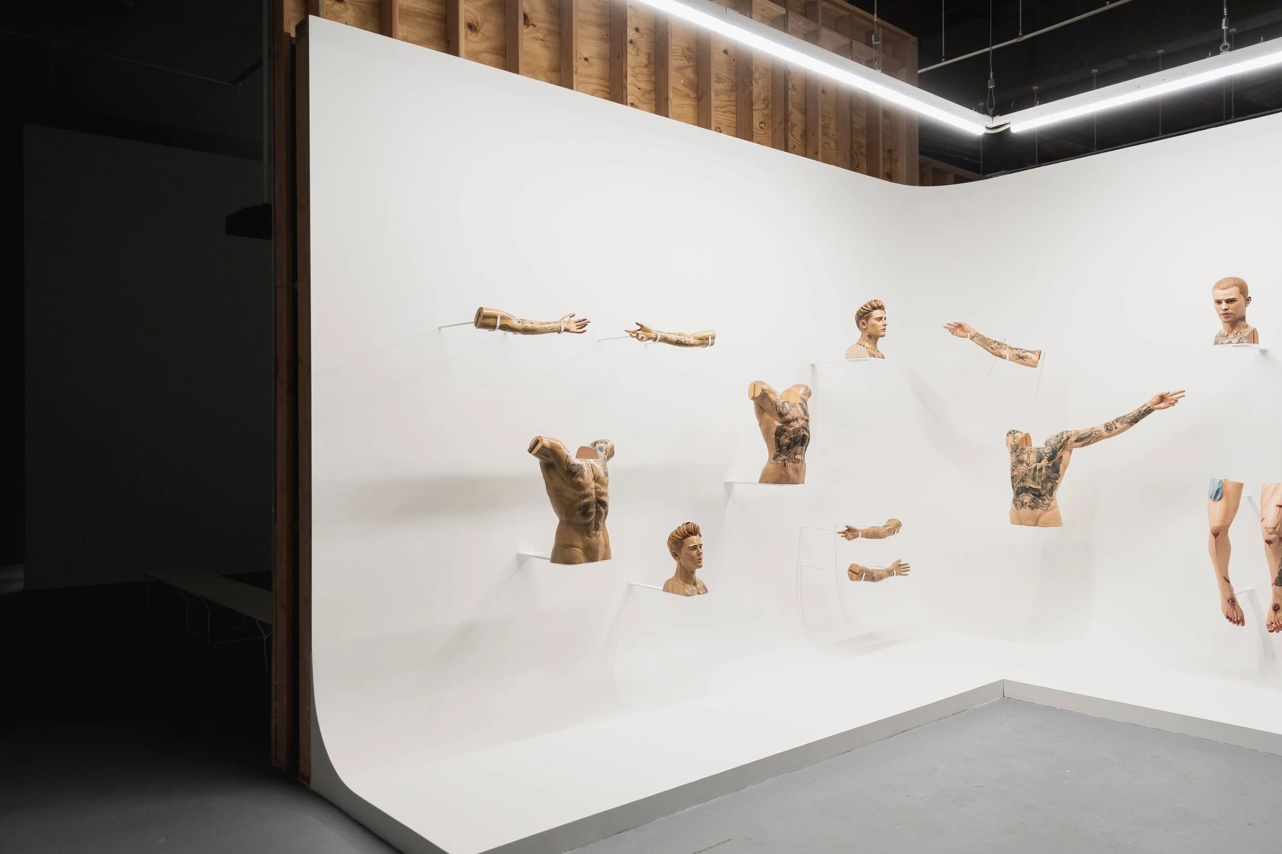 Installation view of Paul Pfeiffer MOCA exhibit featuring lifelike sculptures of human body parts arranged on white backdrop designed by Sparano + Mooney Architecture