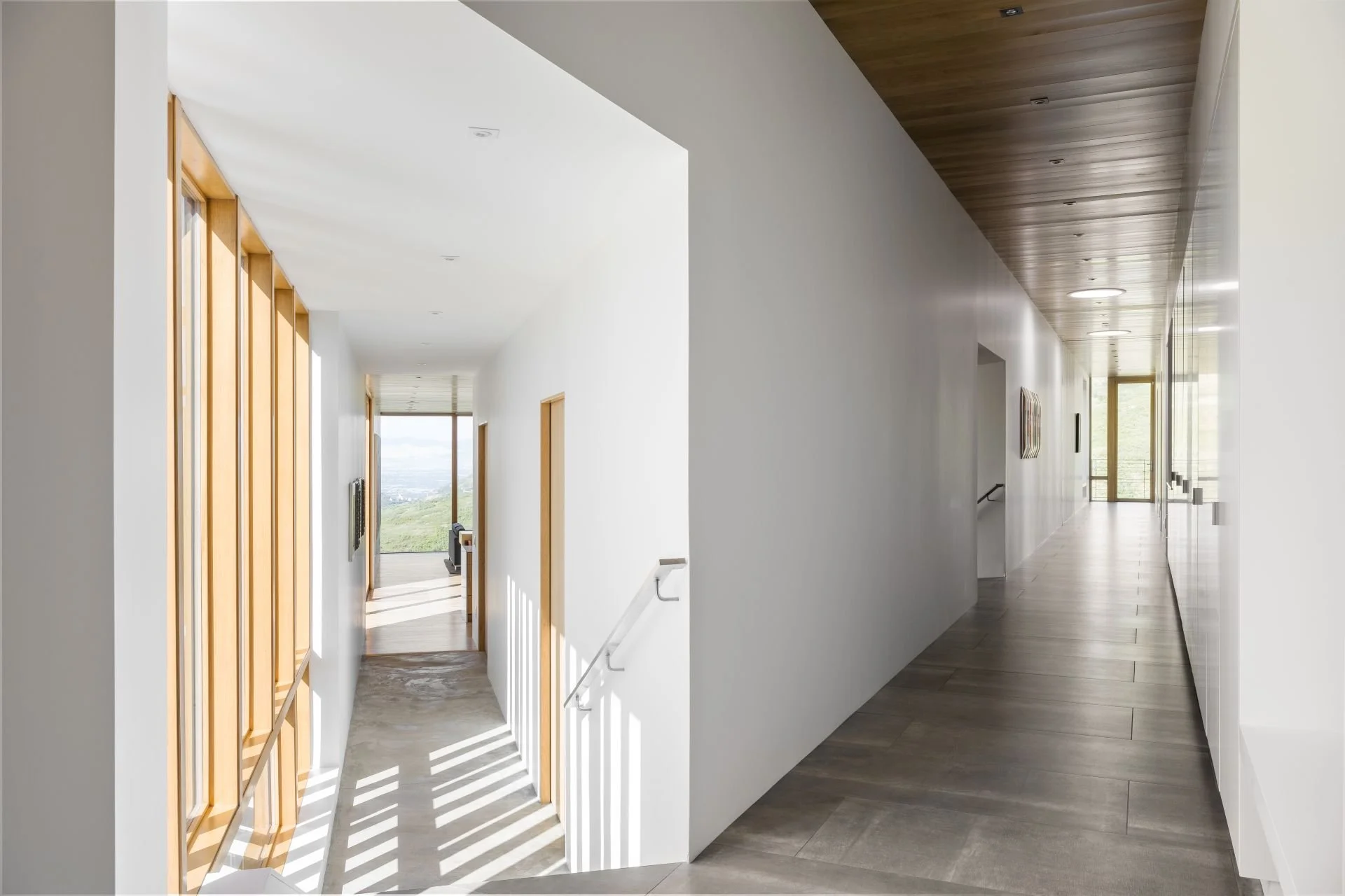 Interior view of Wabi Sabi residence intersecting corridors with concrete floor and light wood framed windows designed by Sparano + Mooney Architecture