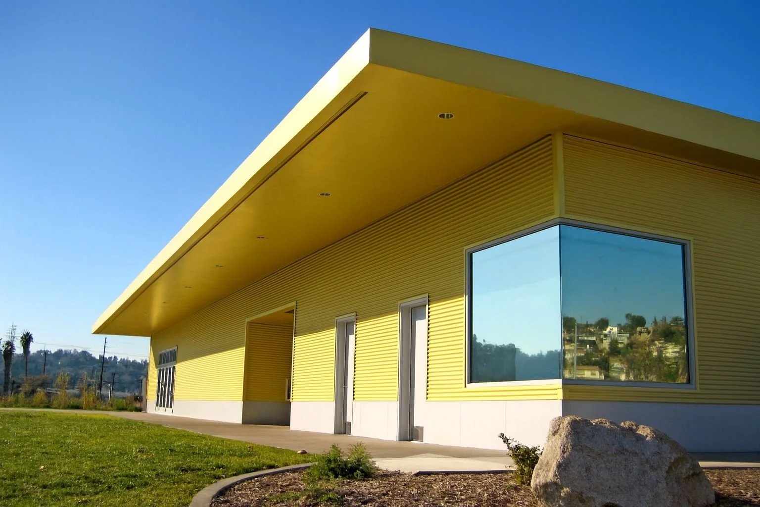 Exterior perspective of yellow facade recreation center with large corner window designed by Sparano + Mooney Architecture