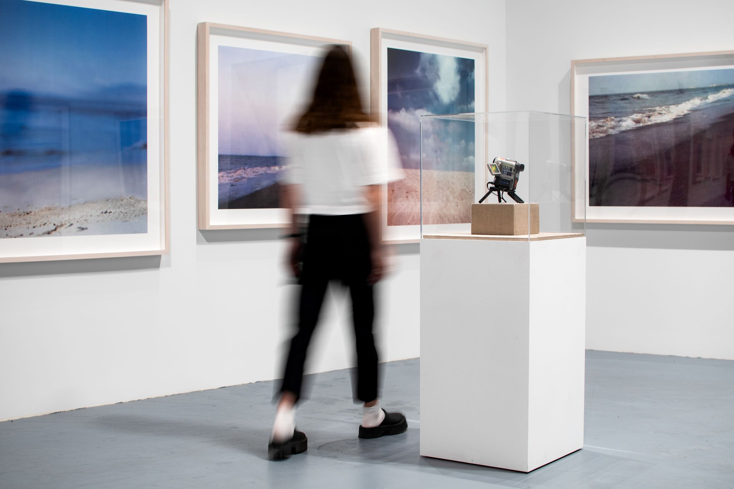 Installation view of Paul Pfeiffer MOCA exhibit featuring a camera on a pedestal and several framed landscape photographs on the walls designed by Sparano + Mooney Architecture