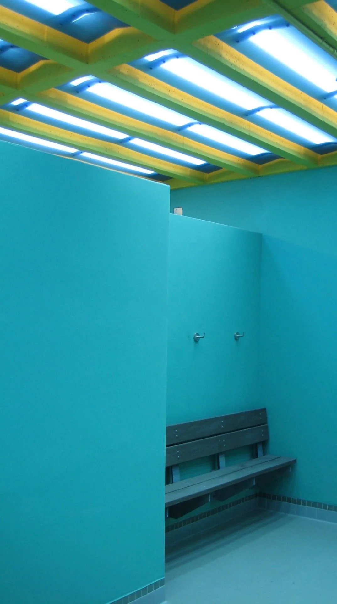 Interior bench in incandescent blue changing room with yellow skylights designed by Sparano + Mooney Architecture.