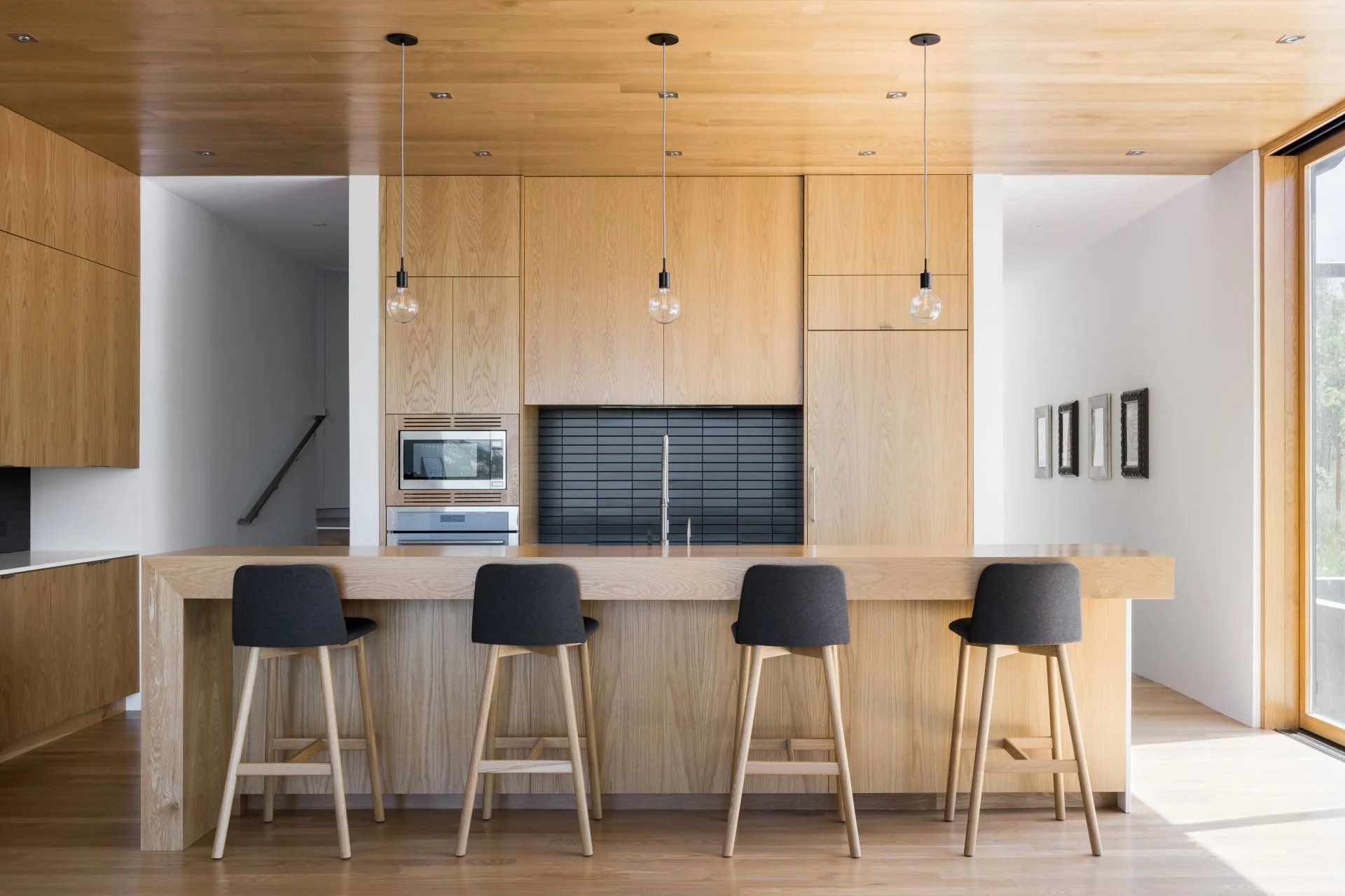 Wabi Sabi modern kitchen with all wood cabinetry and dark grey barstools designed by Sparano + Mooney Architecture