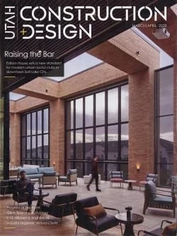 Magazine cover titled "Utah Construction & Design" featuring a modern lobby with large glass windows, brick walls, and various seating areas with people in the space.