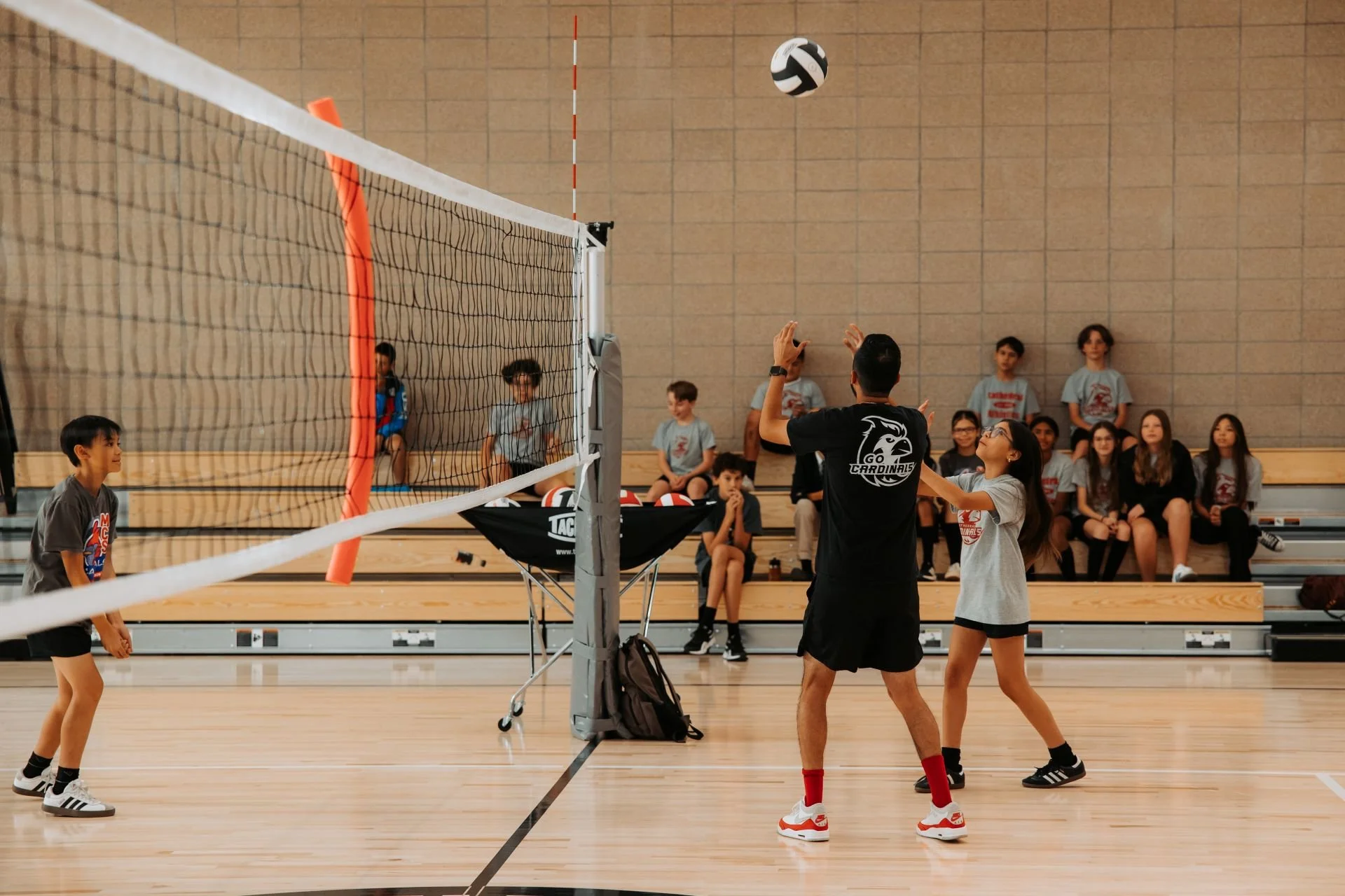 Children and coach playing volleyball in gymnasium designed by Sparano + Mooney Architecture