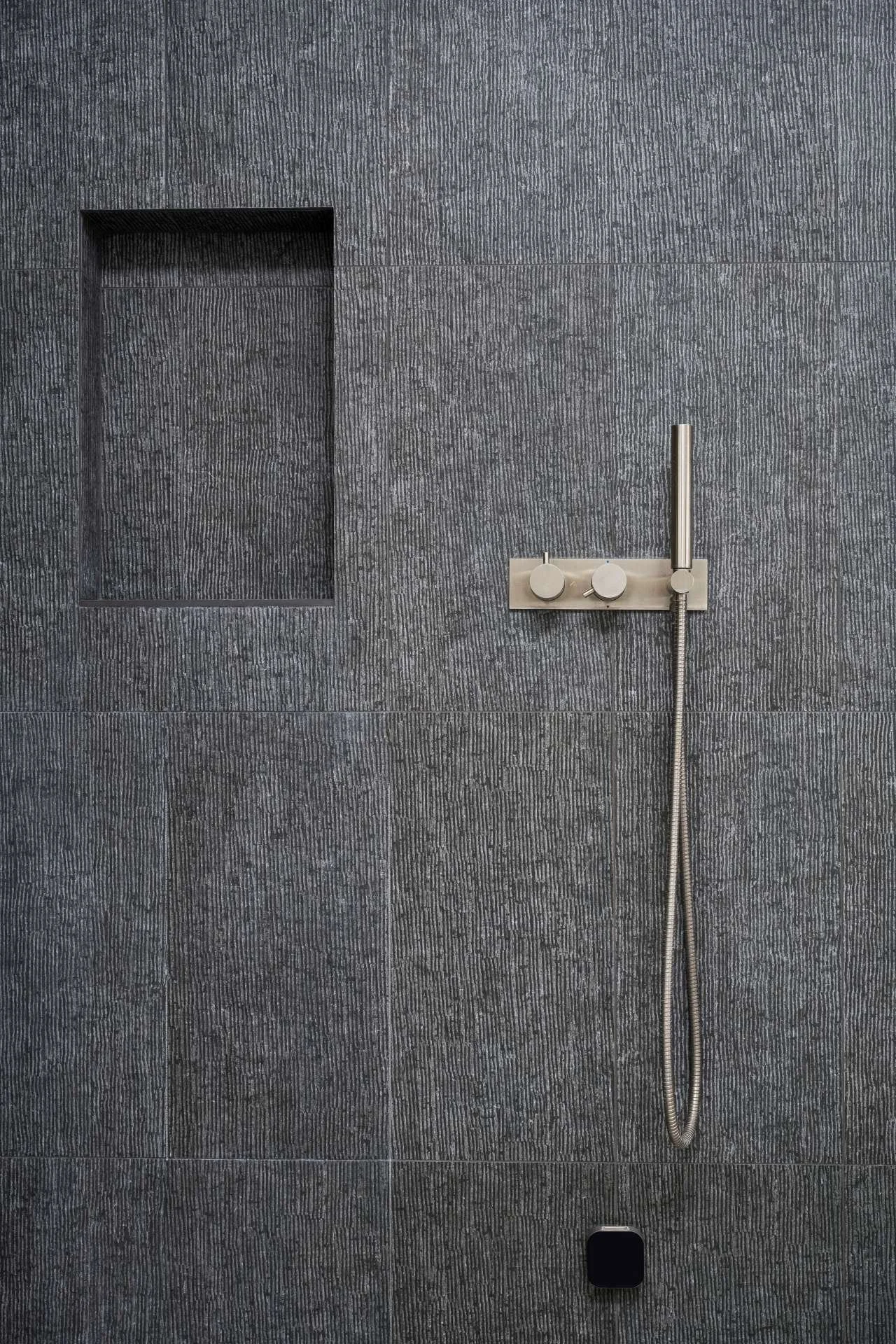 Niche and controls of shower, finished in textured charcoal tile designed by Sparano + Mooney Architecture.