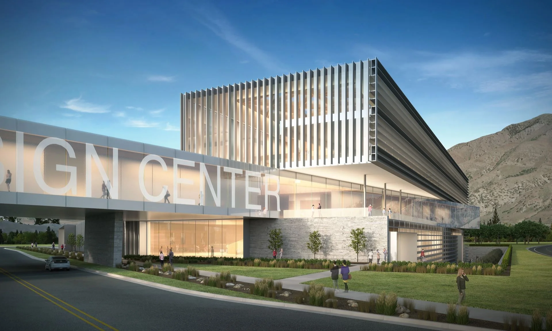Modern building with large glass windows and vertical metal slats, labeled GNC CENTER, surrounded by well-maintained landscaping, with people walking outside and mountains in the background.